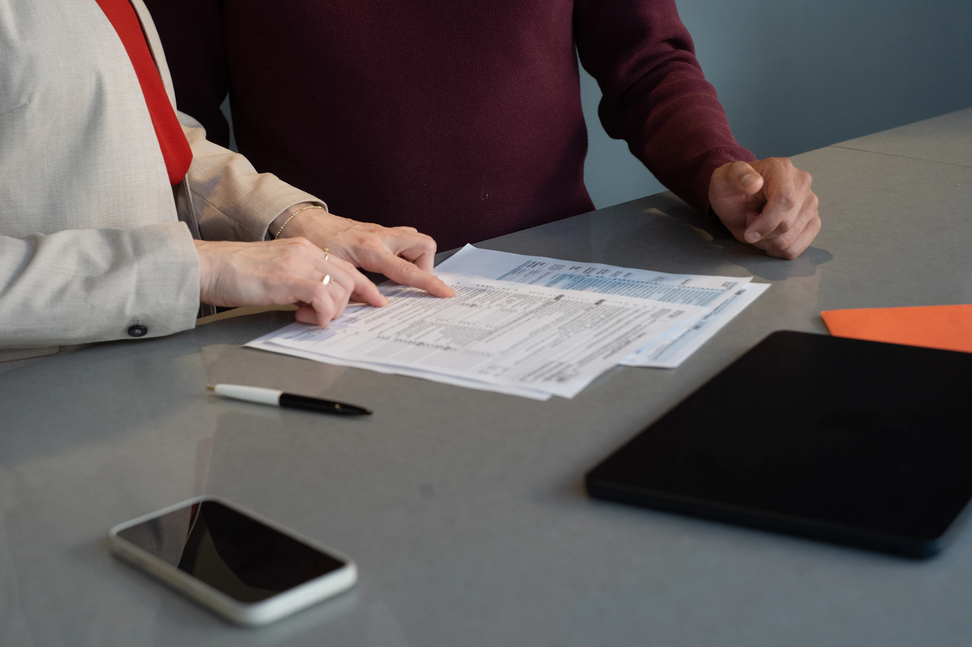 Two people comparing printed documents across a desk