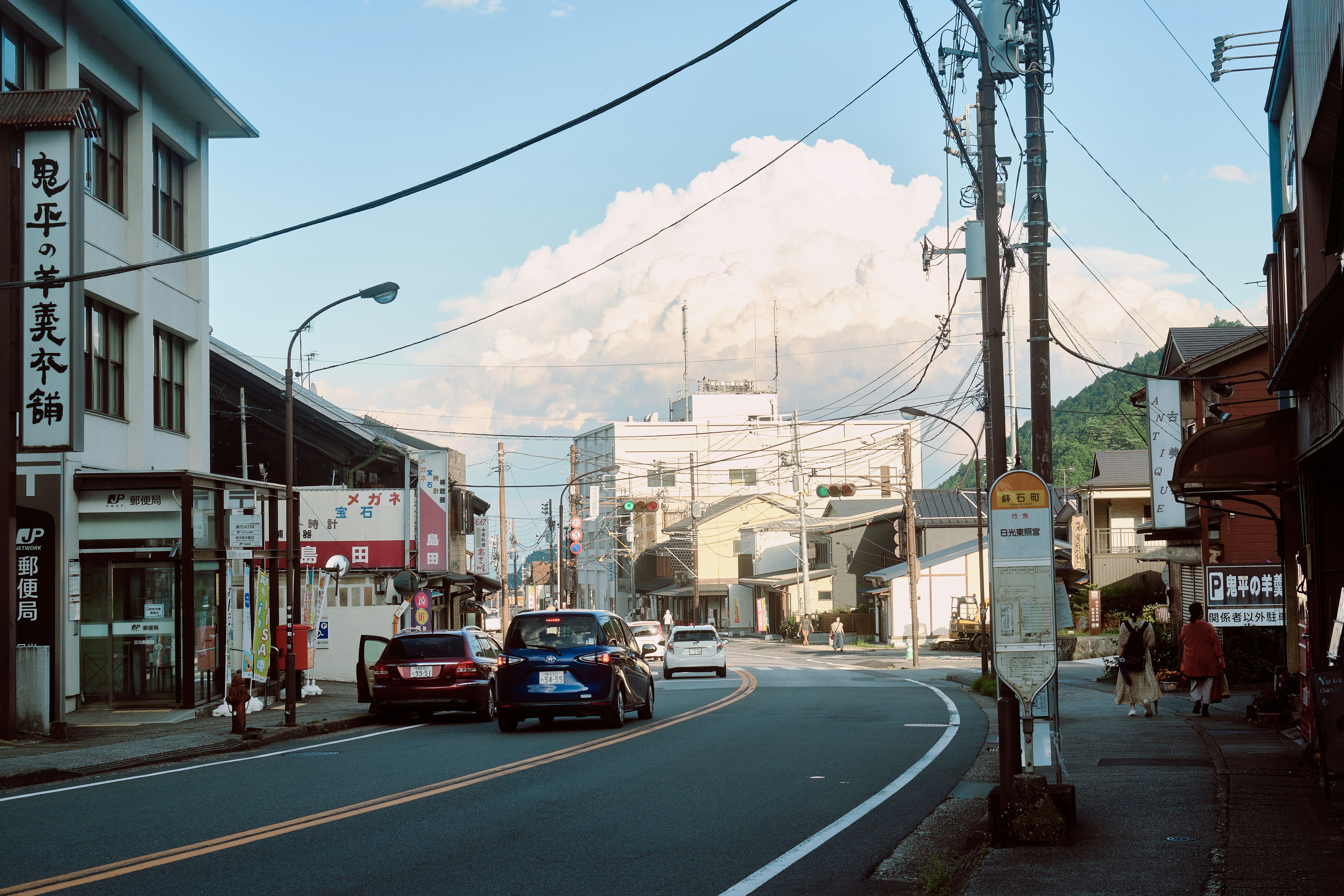 Mount fuji looms over a quiet street with cars.