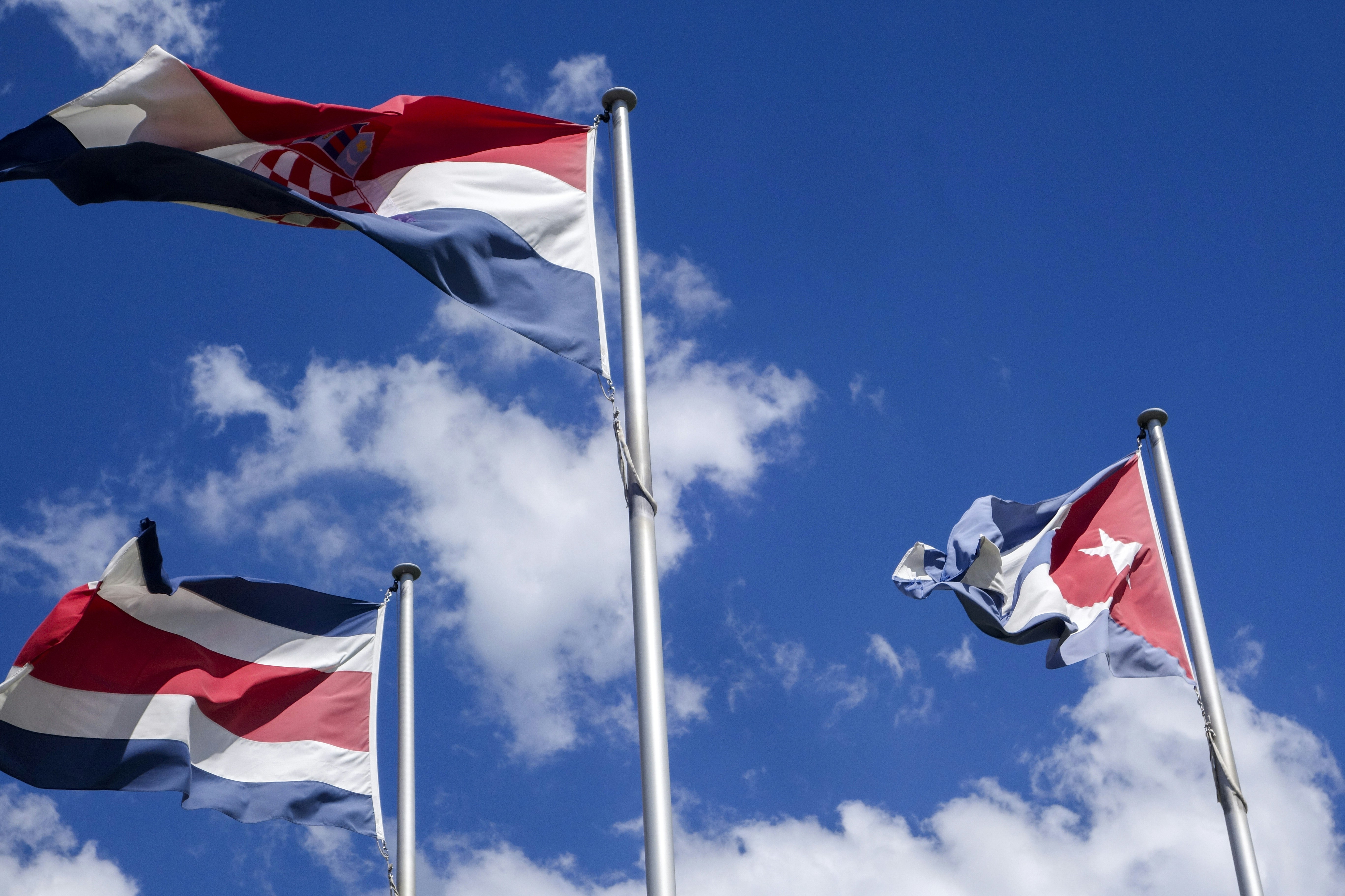 Three national flags waving against a blue sky