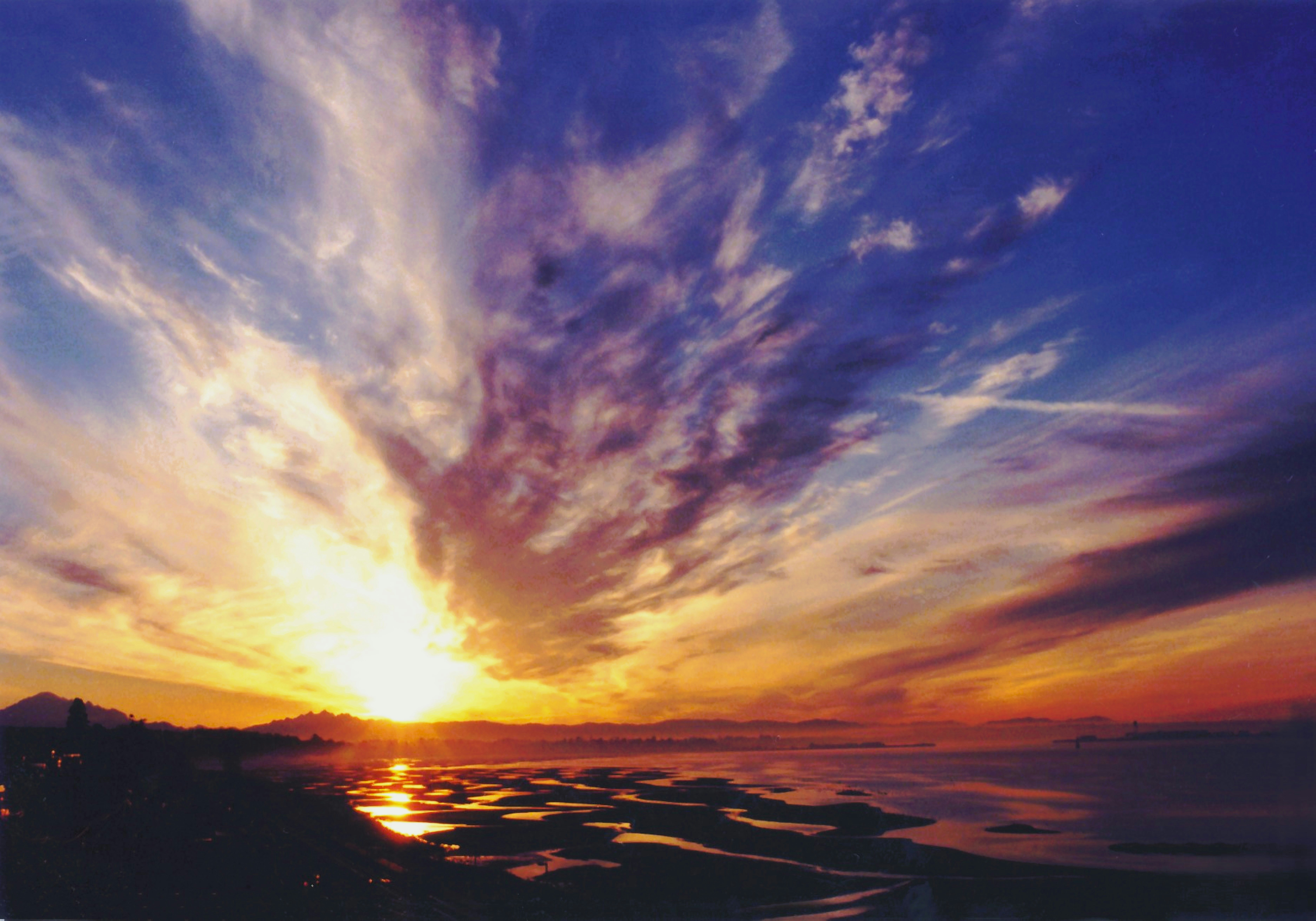 Dramatic sunset sky over a coastal landscape.