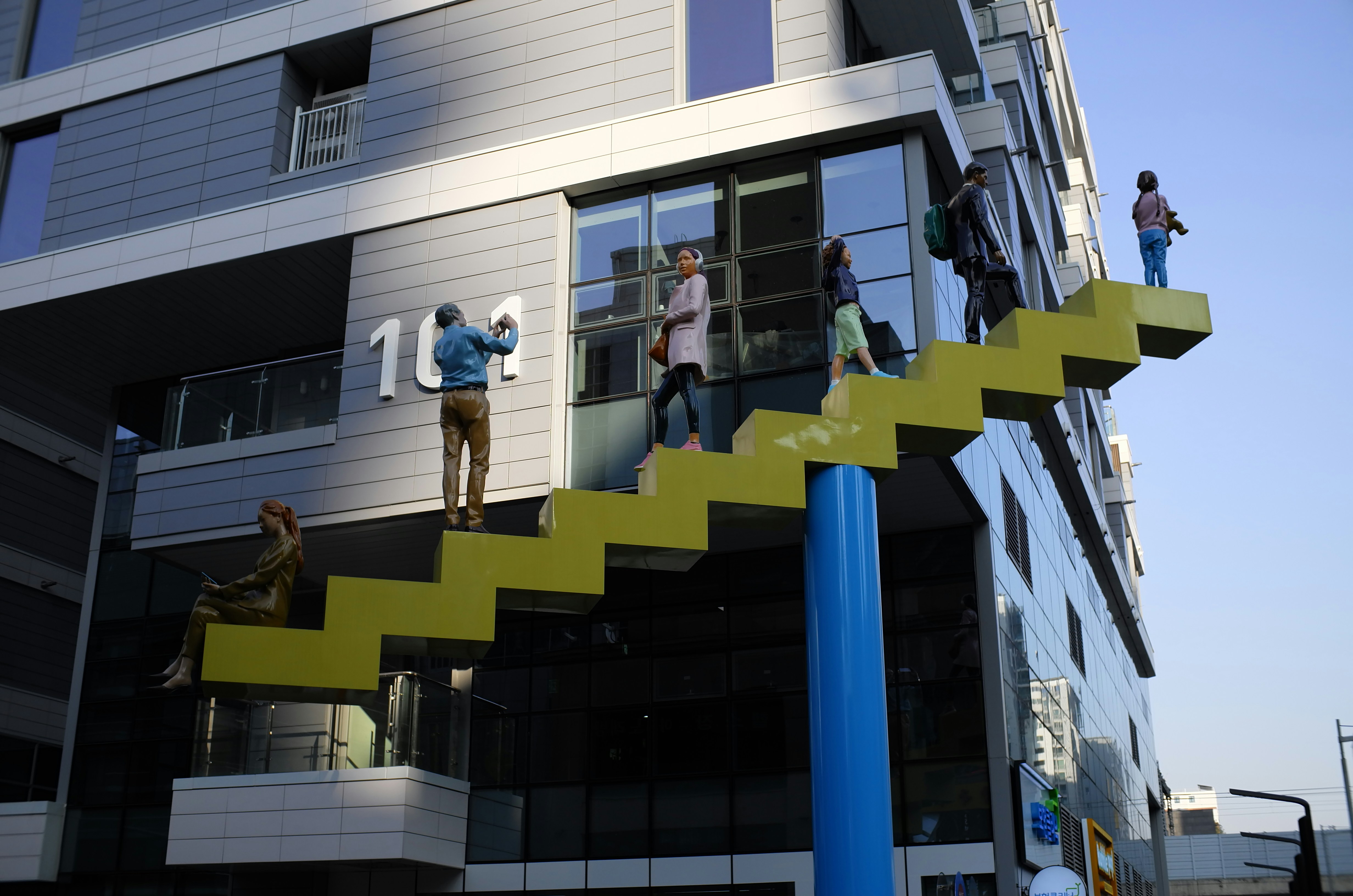 People on a bright yellow outdoor staircase on building.