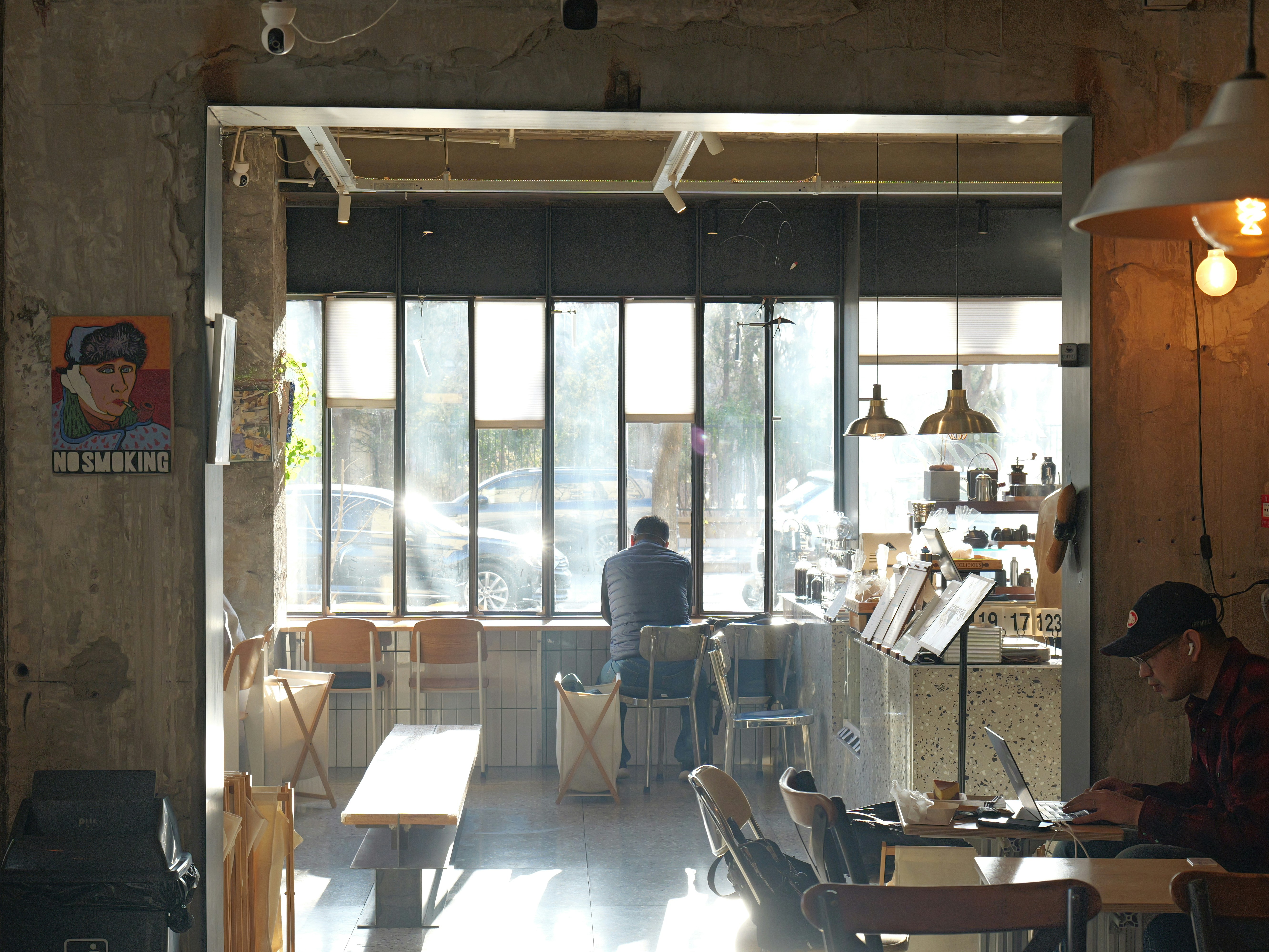 Man working on laptop in a sunlit cafe.