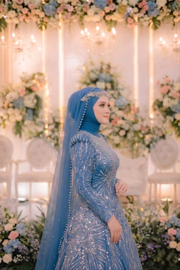 A bride in a blue sequined dress and hijab.