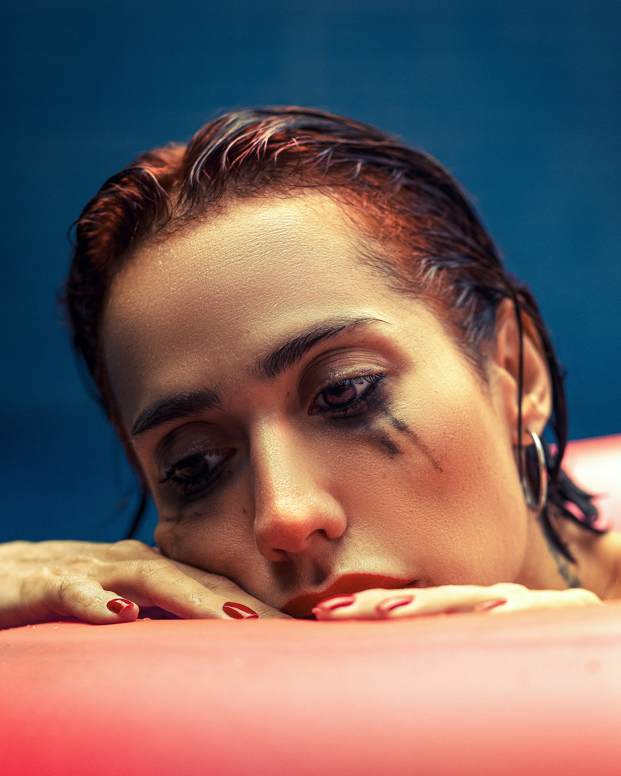 Donna con il trucco sbavato appoggia il mento sulle mani.
