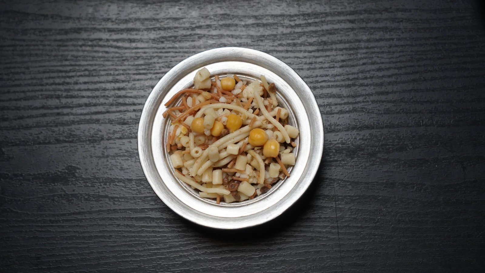 Illustrative image for vegan food in cairo: ful, taameya and koshari: A white bowl of koshary layered with pasta, rice, lentils, chickpeas and fried onion.