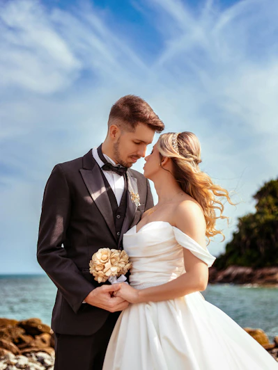 A bride and groom embrace on a beach