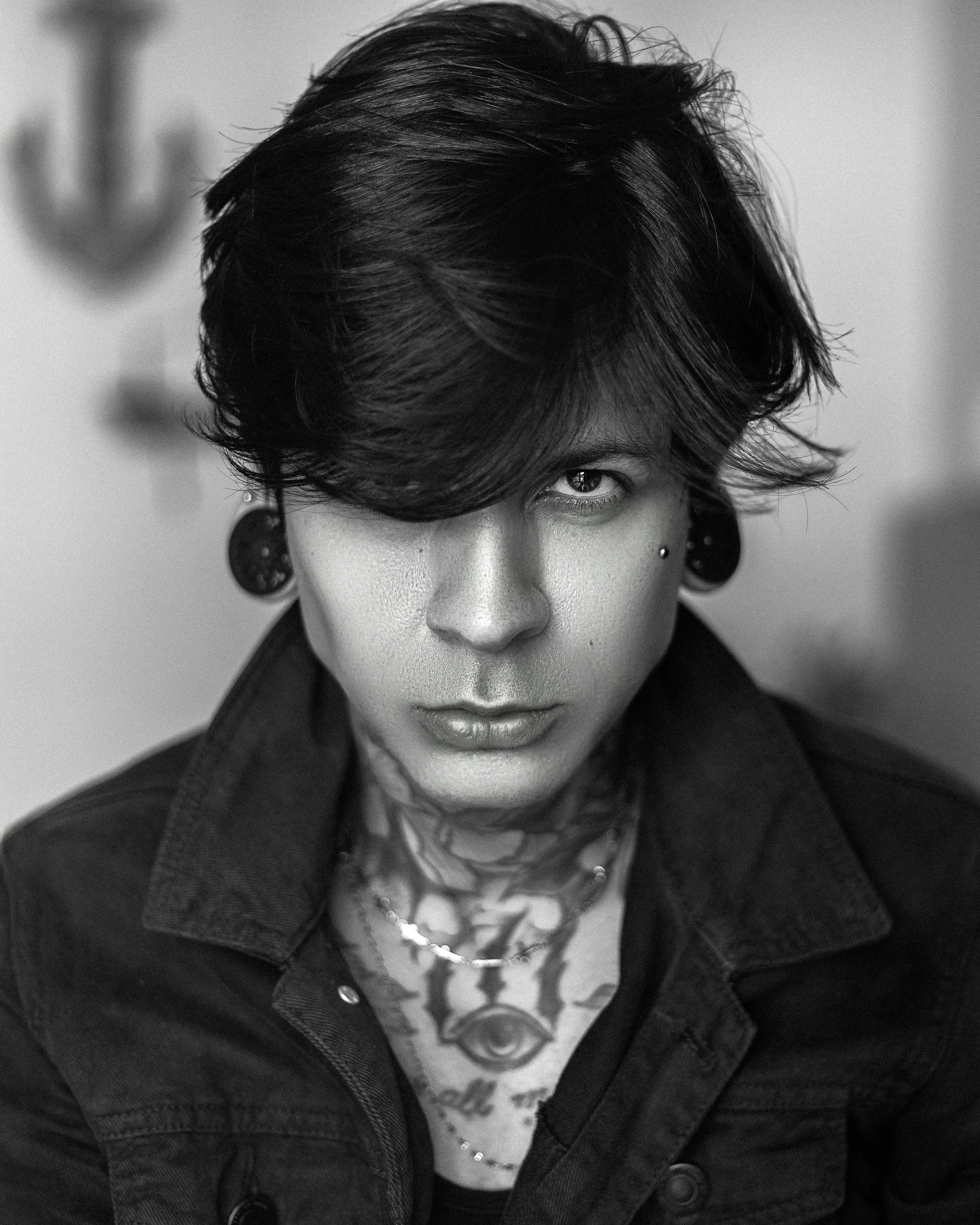 Man with tattoos and ear gauges looking intensely.