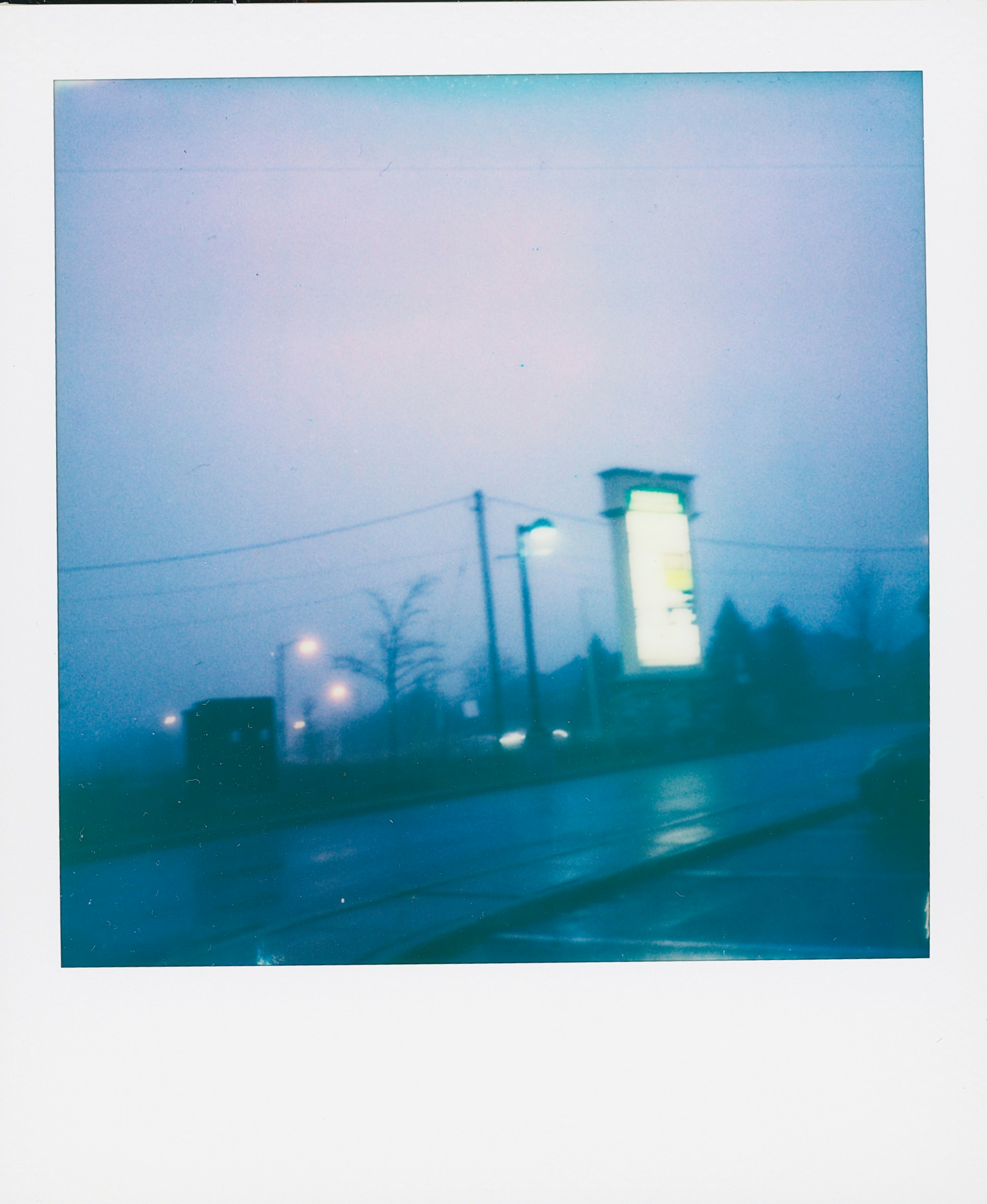 Uma cena de rua na névoa com luzes brilhantes.