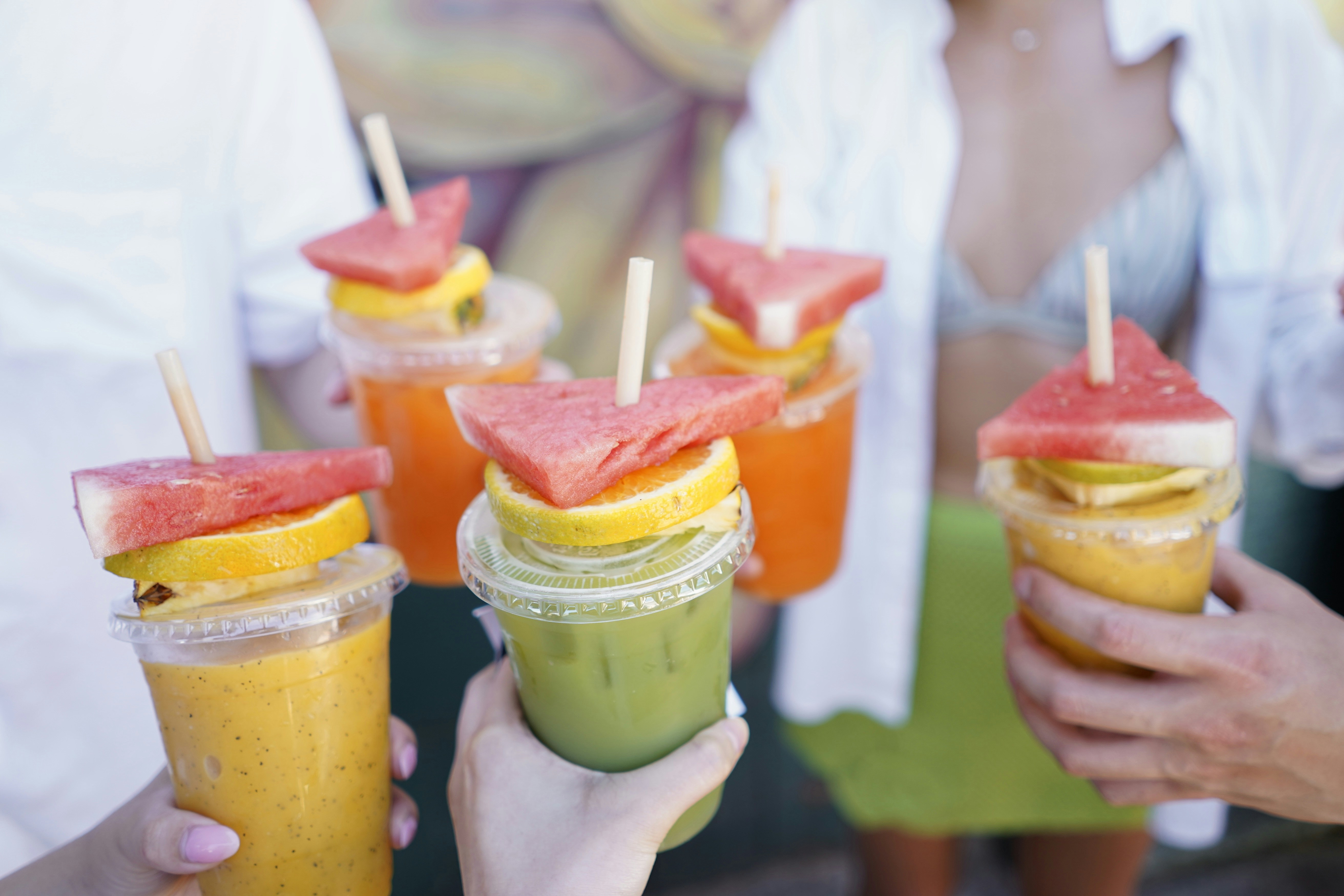 Des gens tenant des smoothies aux fruits colorés avec une décoration de pastèque