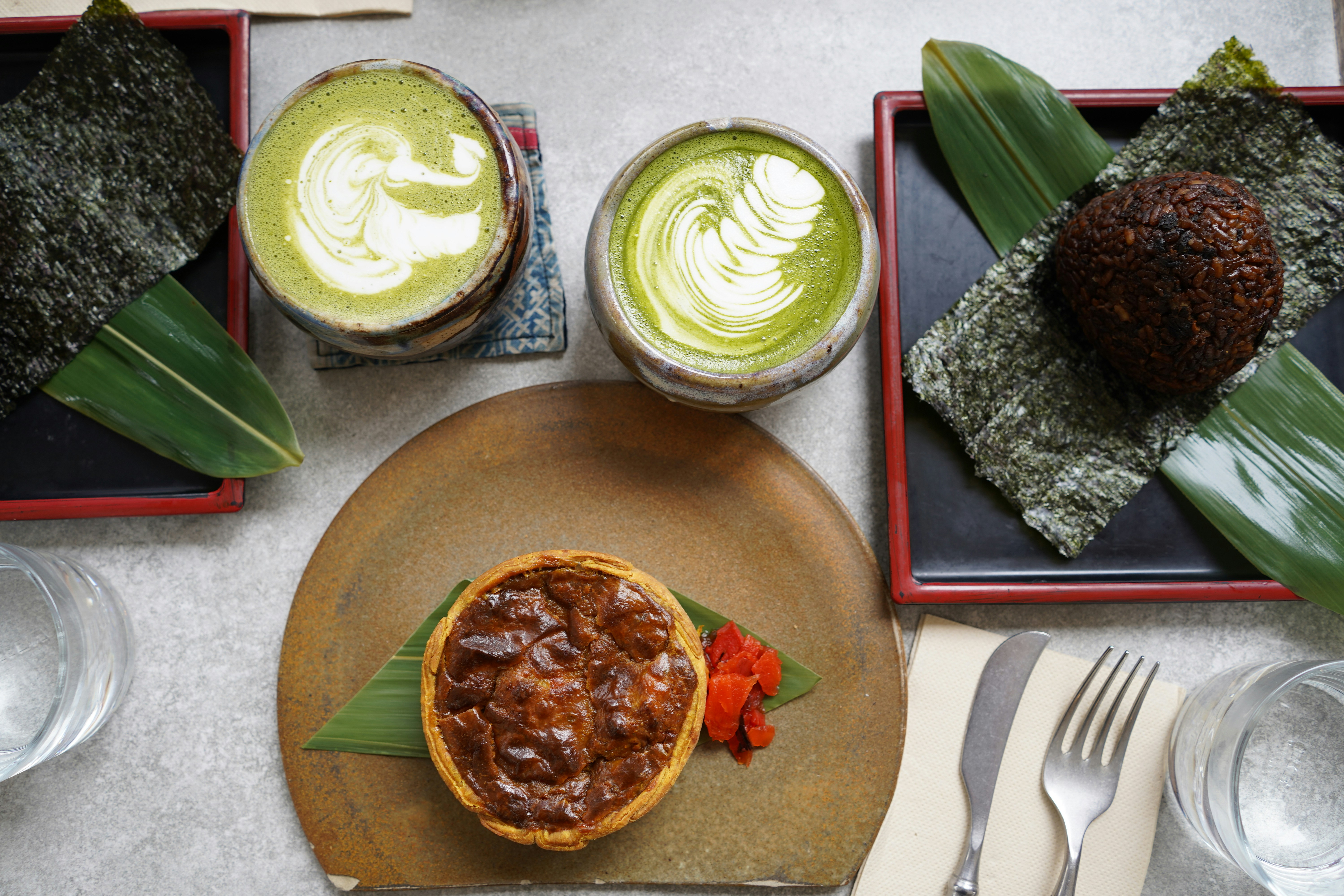 Deux lattes matcha avec une pâtisserie et une boulette de riz