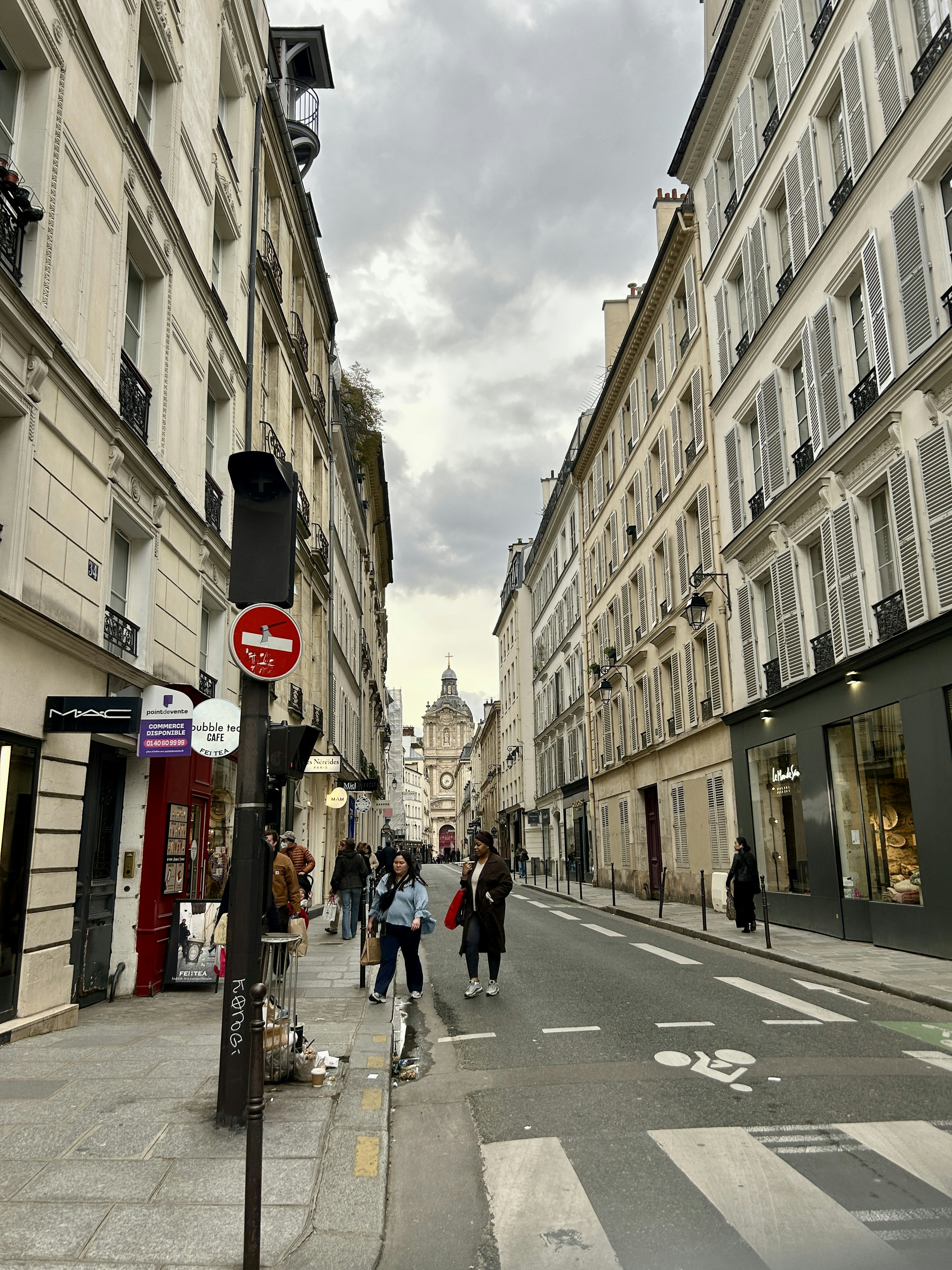 Narrow parisian street with shops and pedestrians