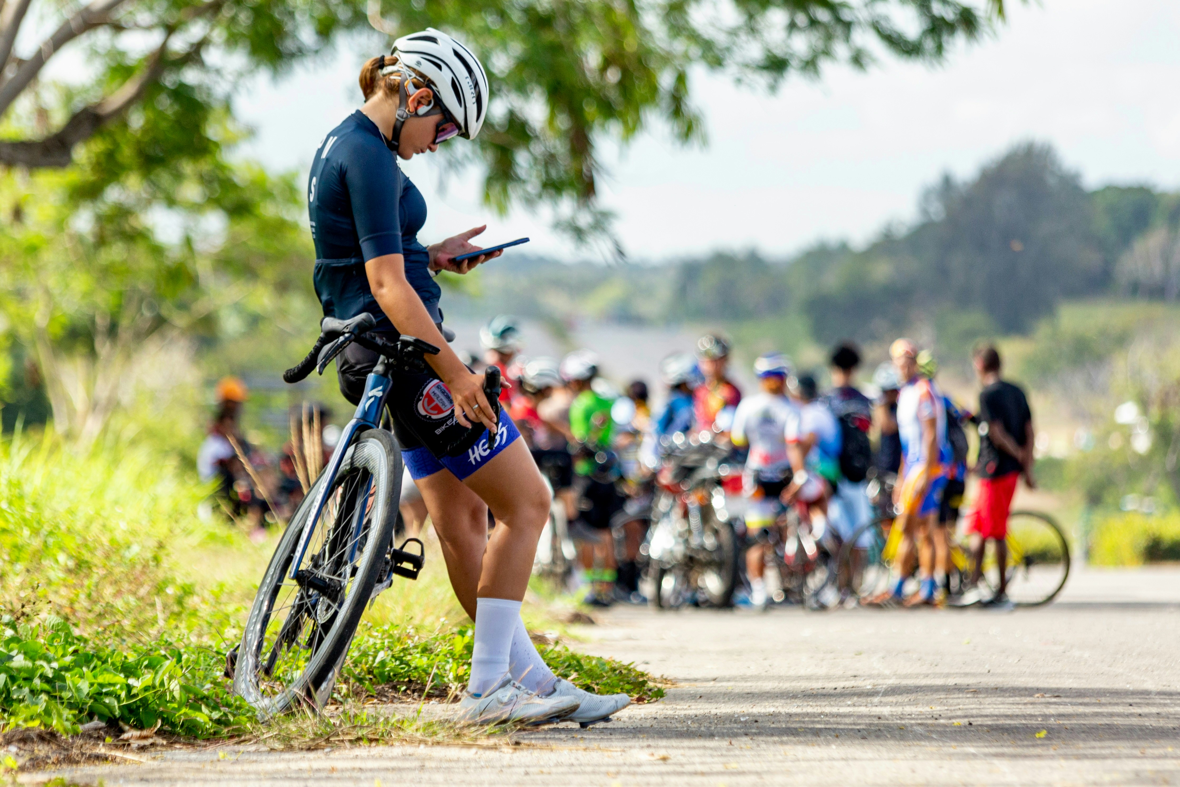 Cyclist looking at phone with group behind