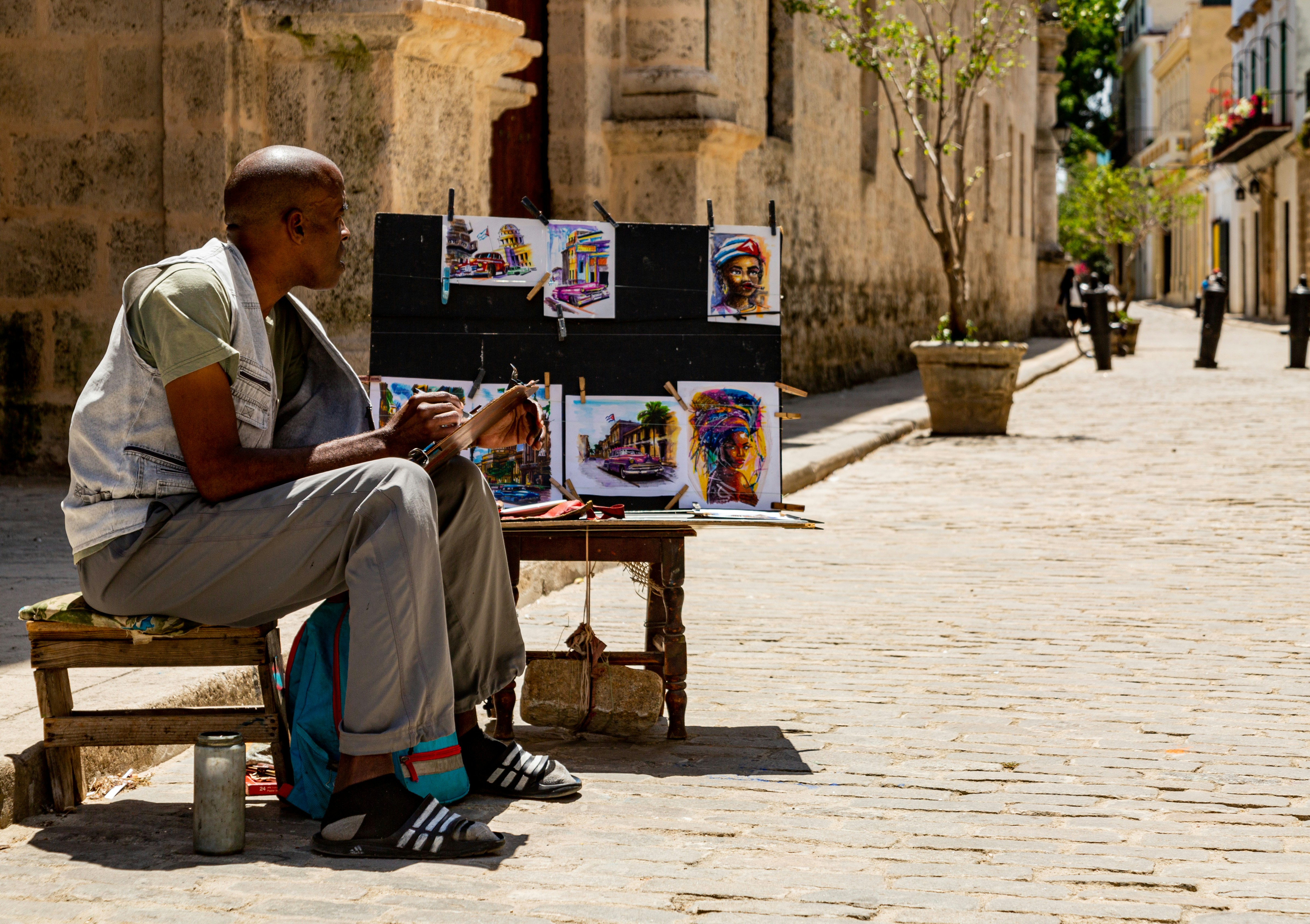 L’artiste expose des tableaux dans une rue ensoleillée.