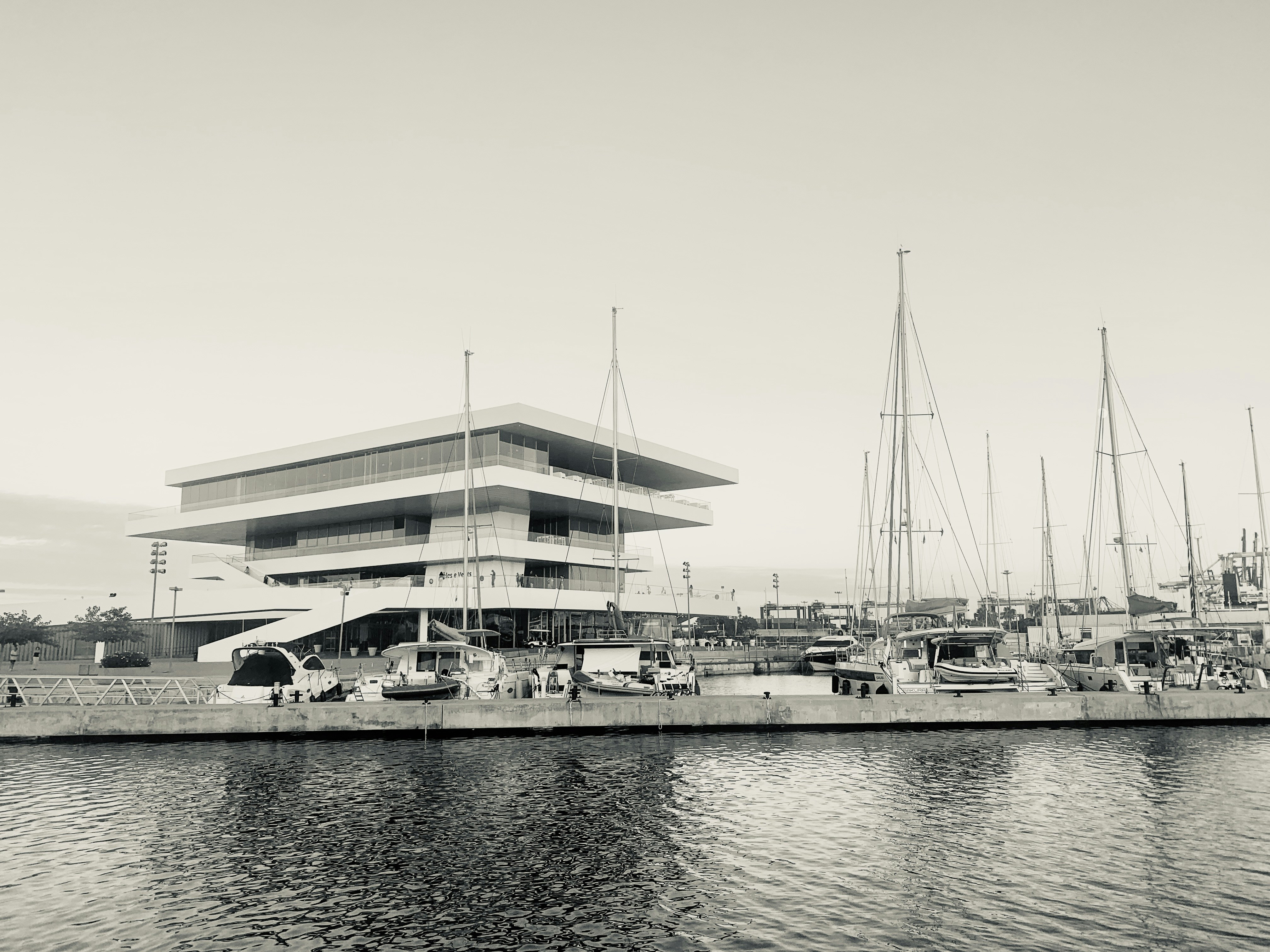 Edificio moderno con veleros atracados en la marina.