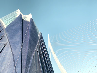 Modern skyscraper and suspension bridge against clear sky