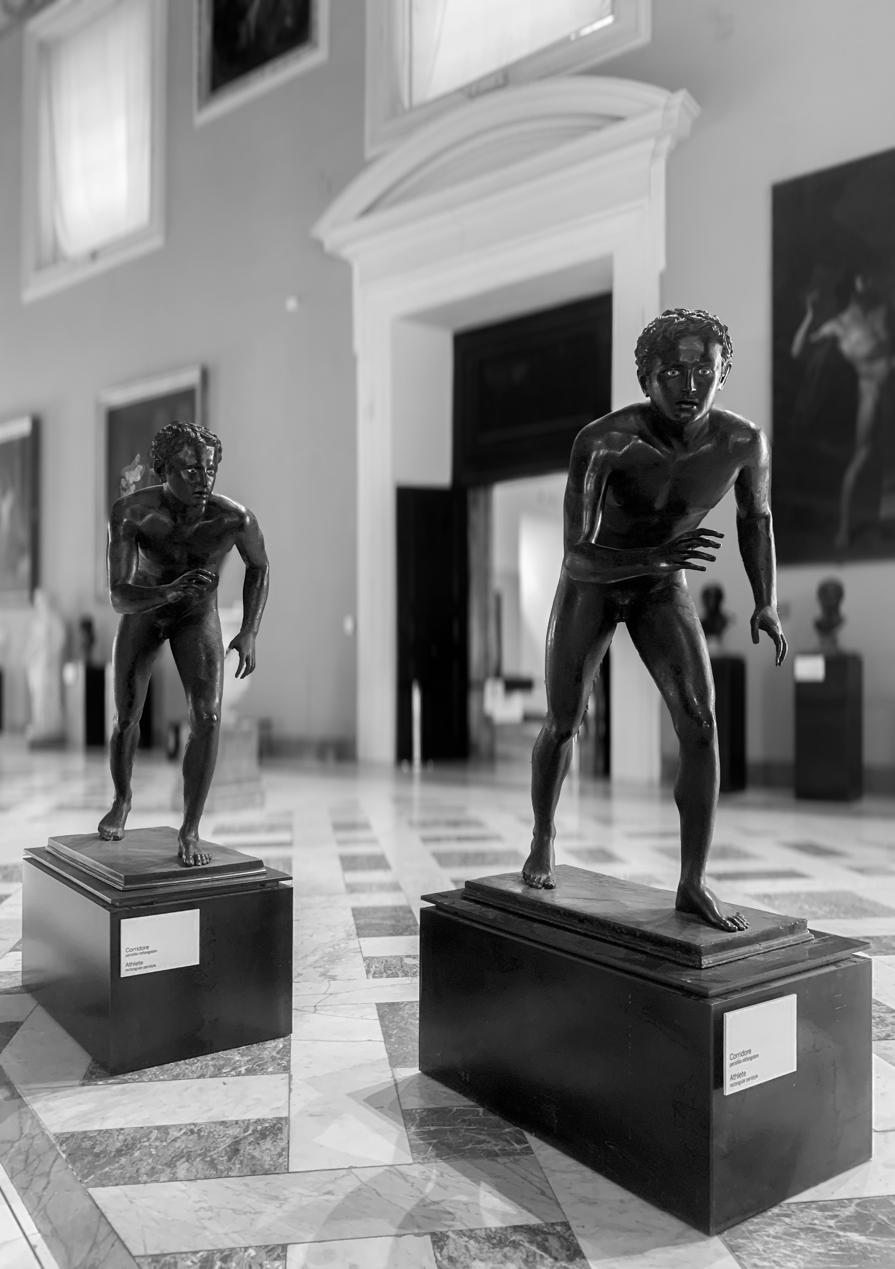 Dos estatuas de bronce de atletas en un salón de museo.