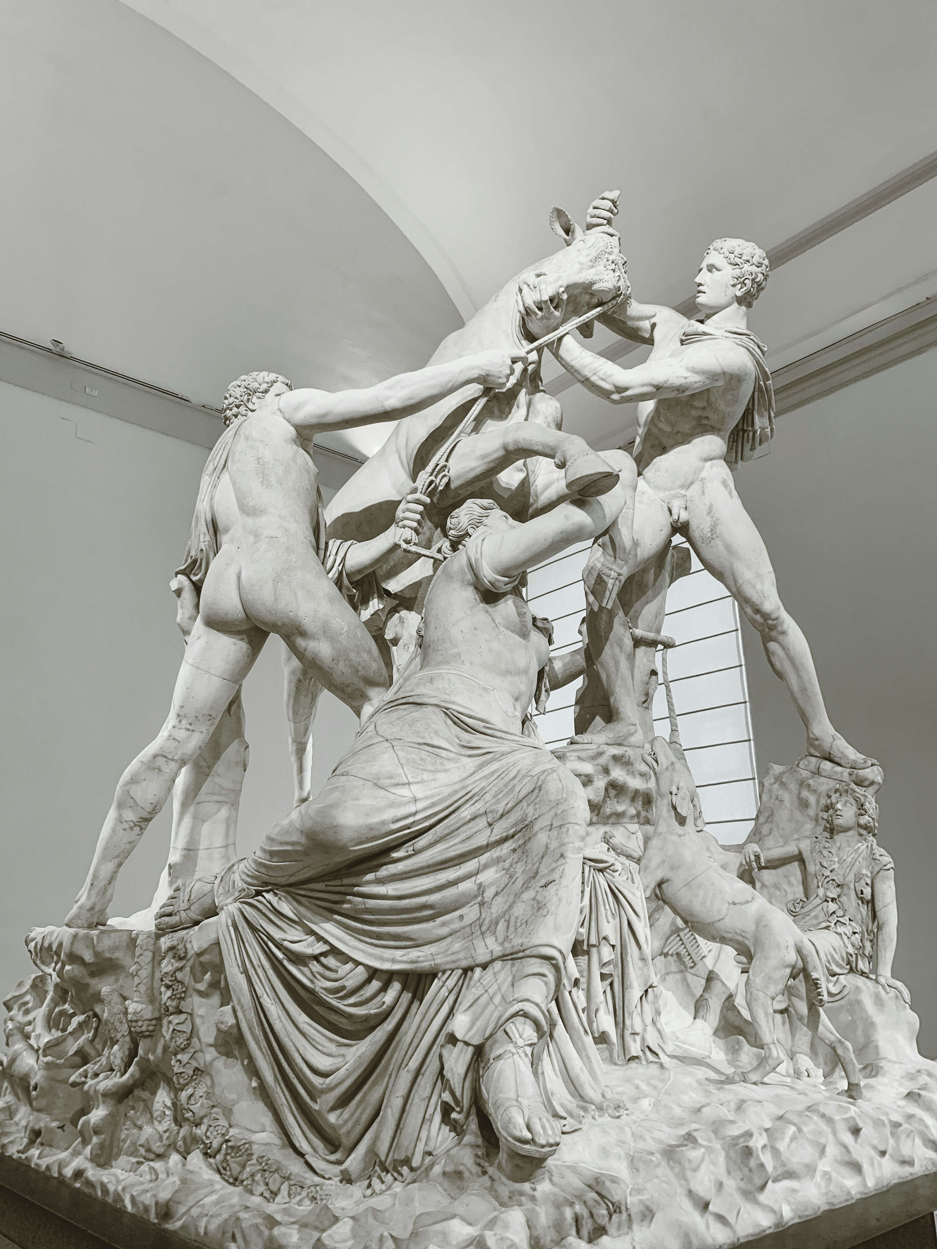 Escultura de mármol de hombres luchando con un caballo