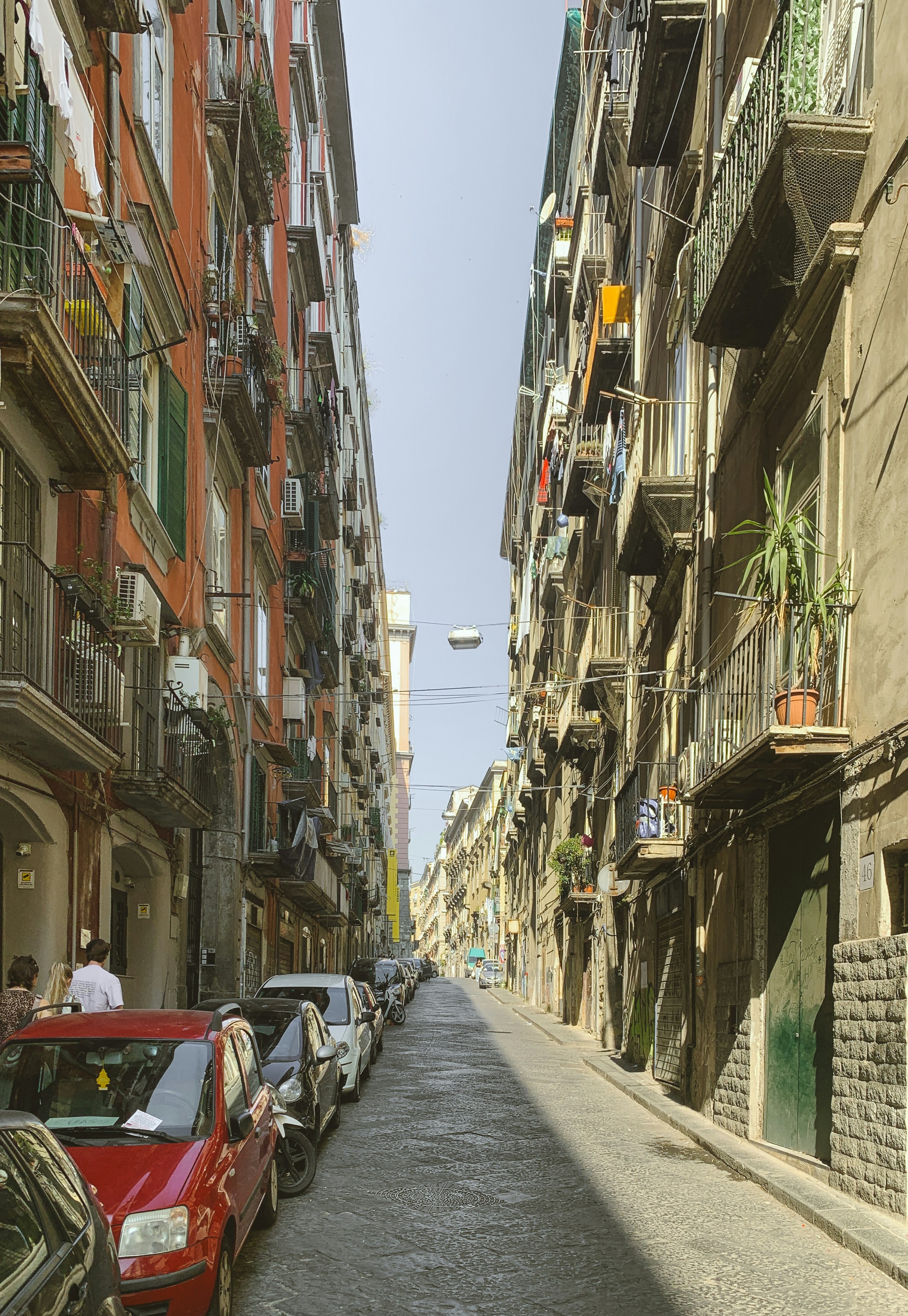 Calle estrecha bordeada de edificios antiguos y coches aparcados.