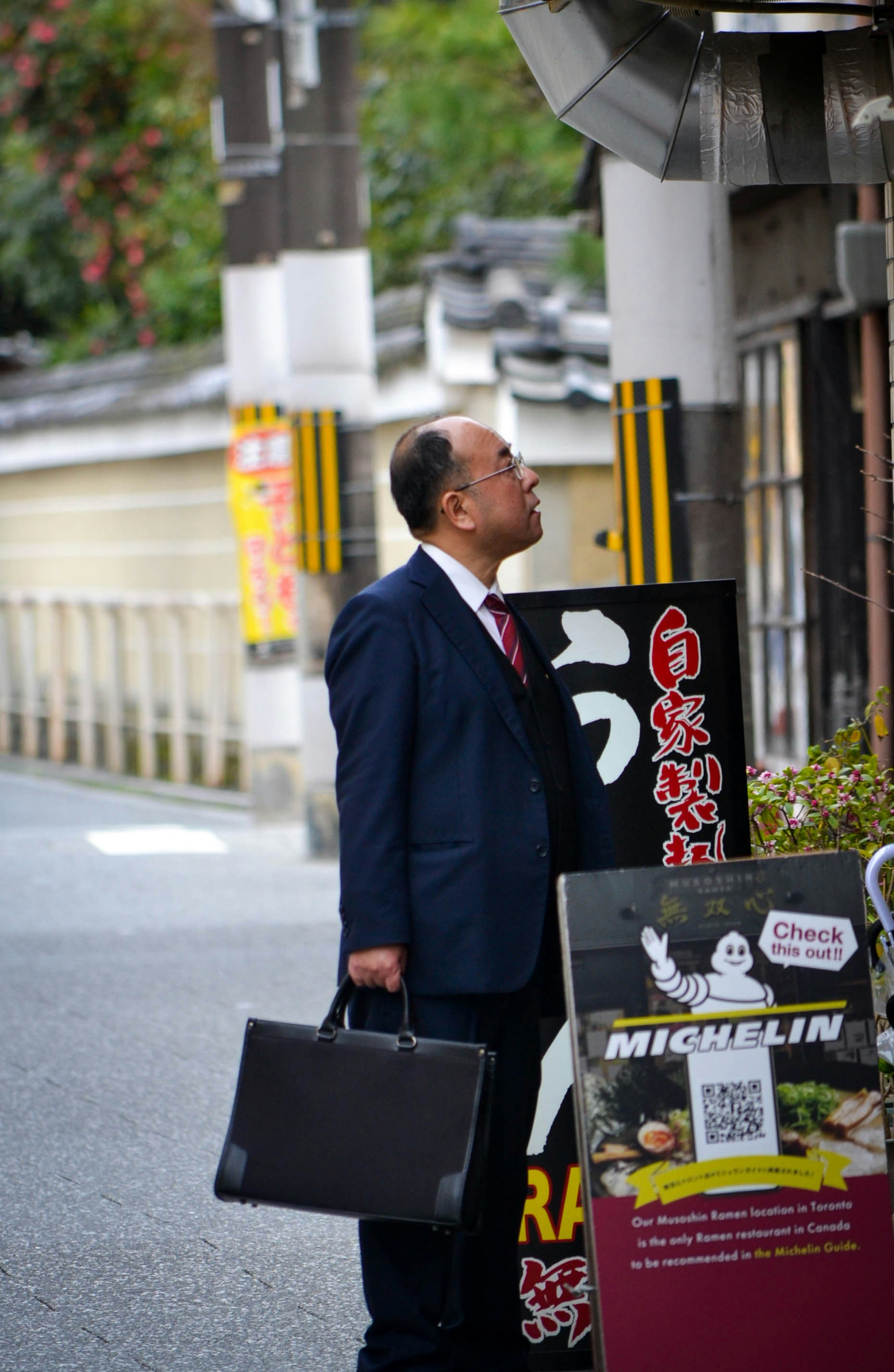 Man in suit looks at a sign on a street.