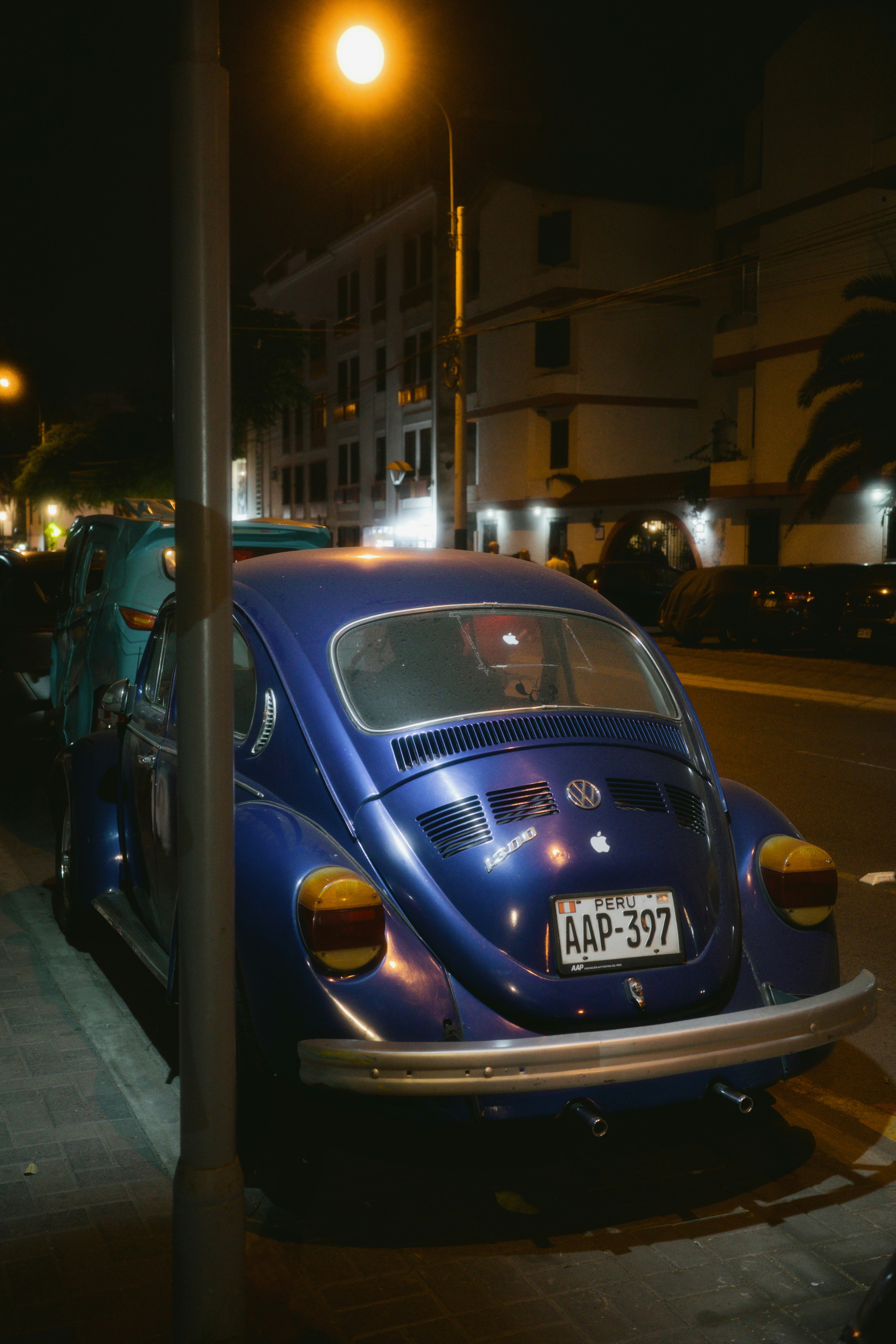 A blue volkswagen beetle parked at night.
