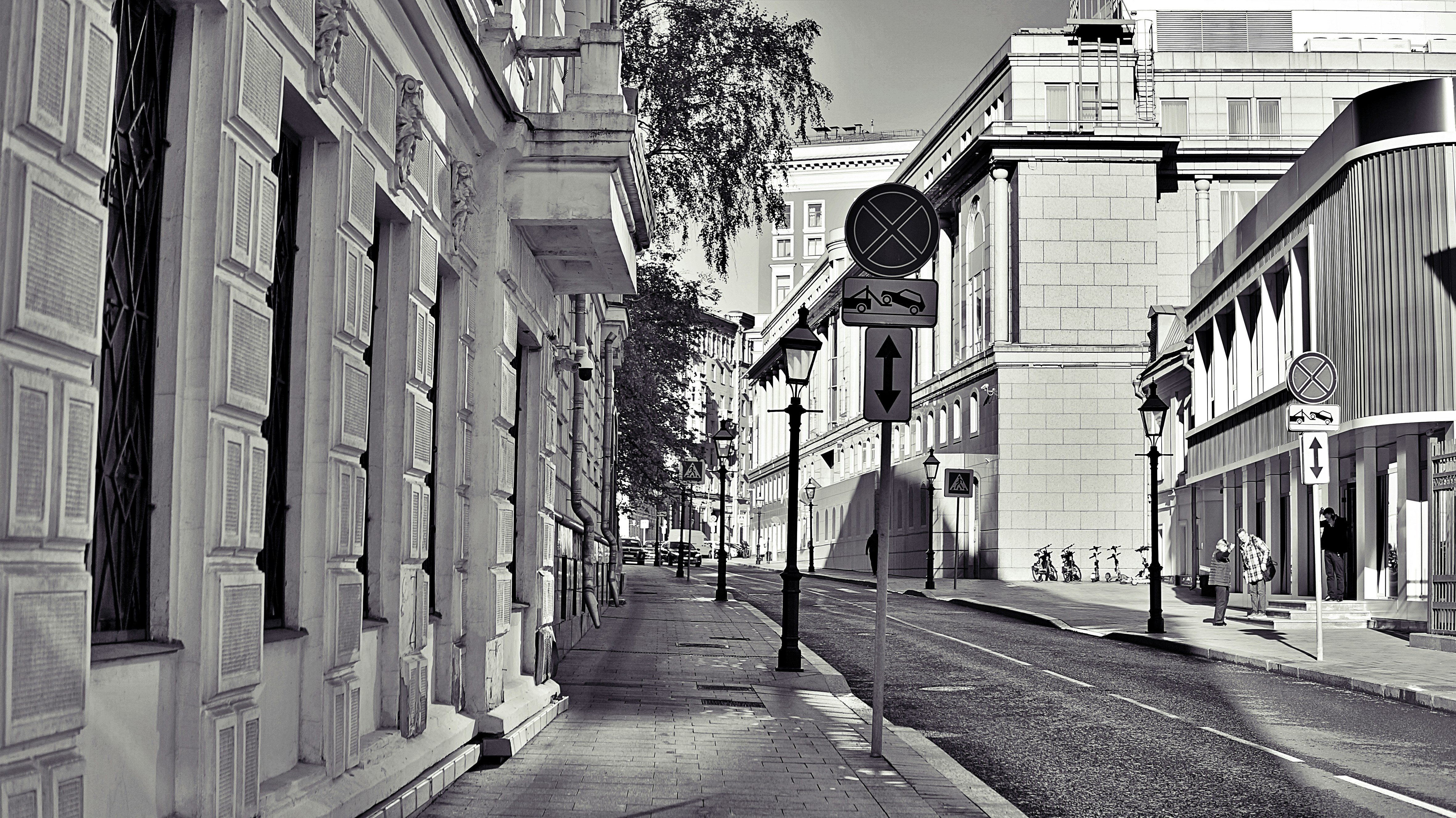 Black and white street view with buildings and sidewalk.