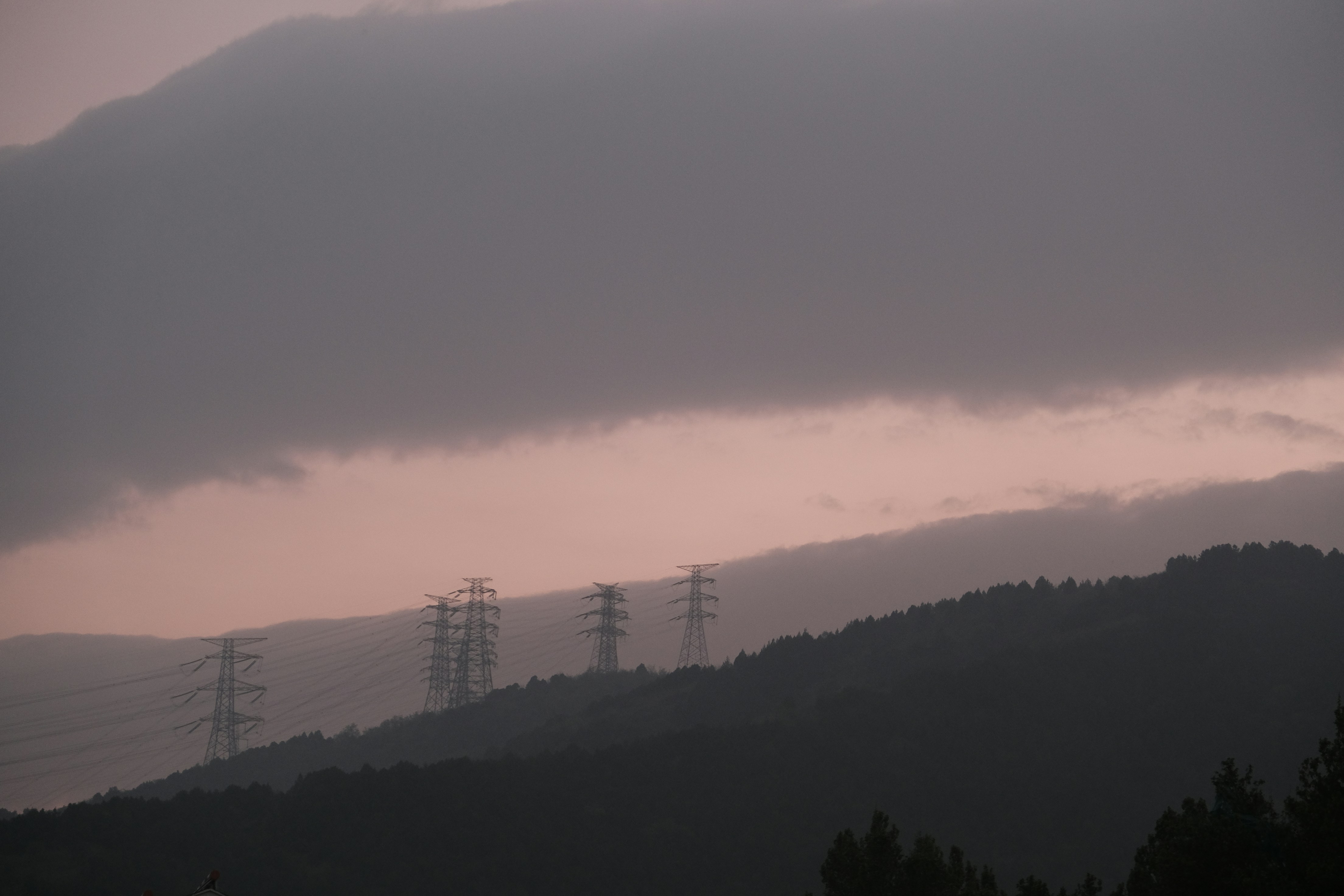 Power lines on a misty mountain landscape at dusk