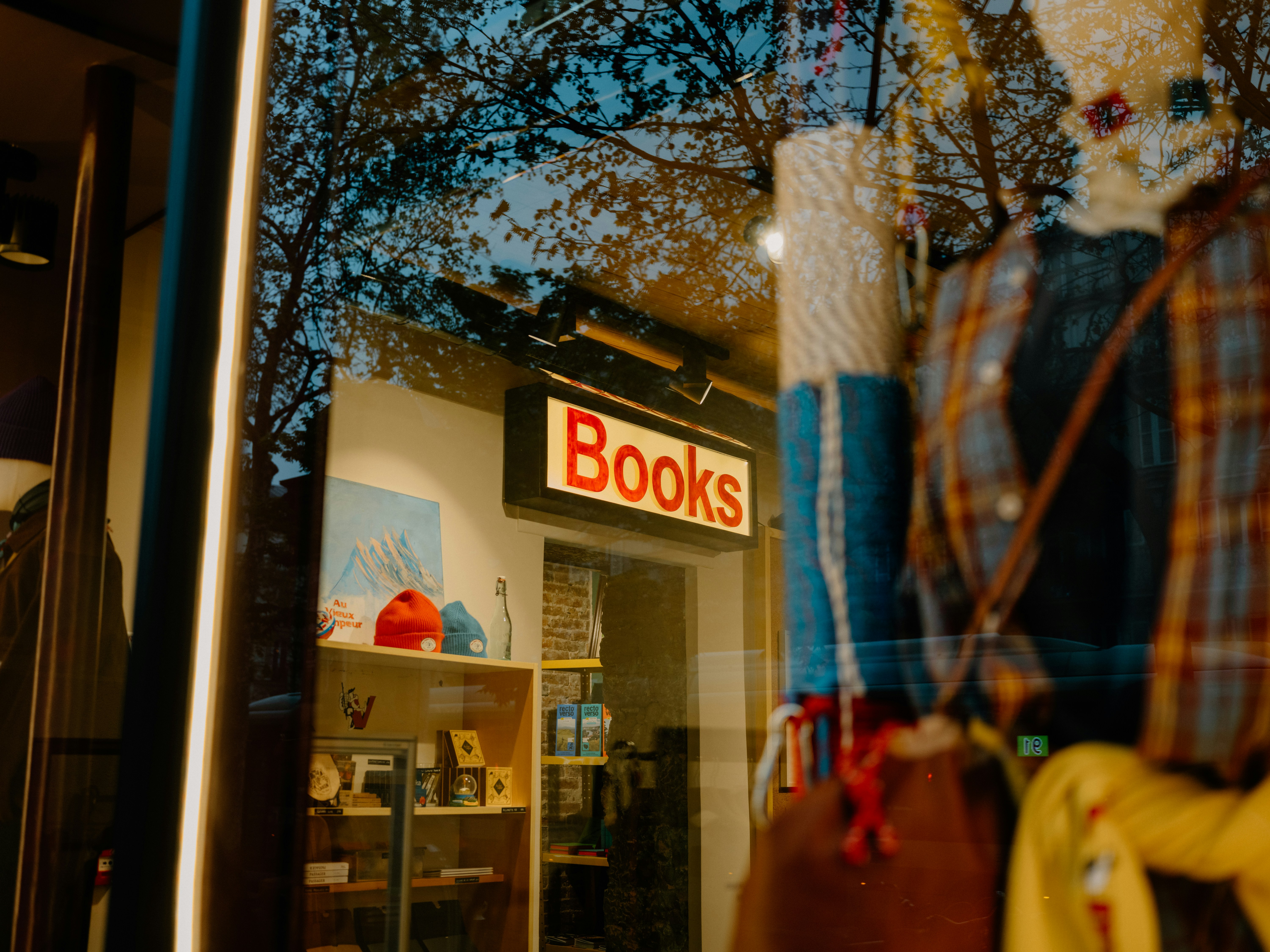 Placa de livros refletida na vitrine de uma loja ao entardecer