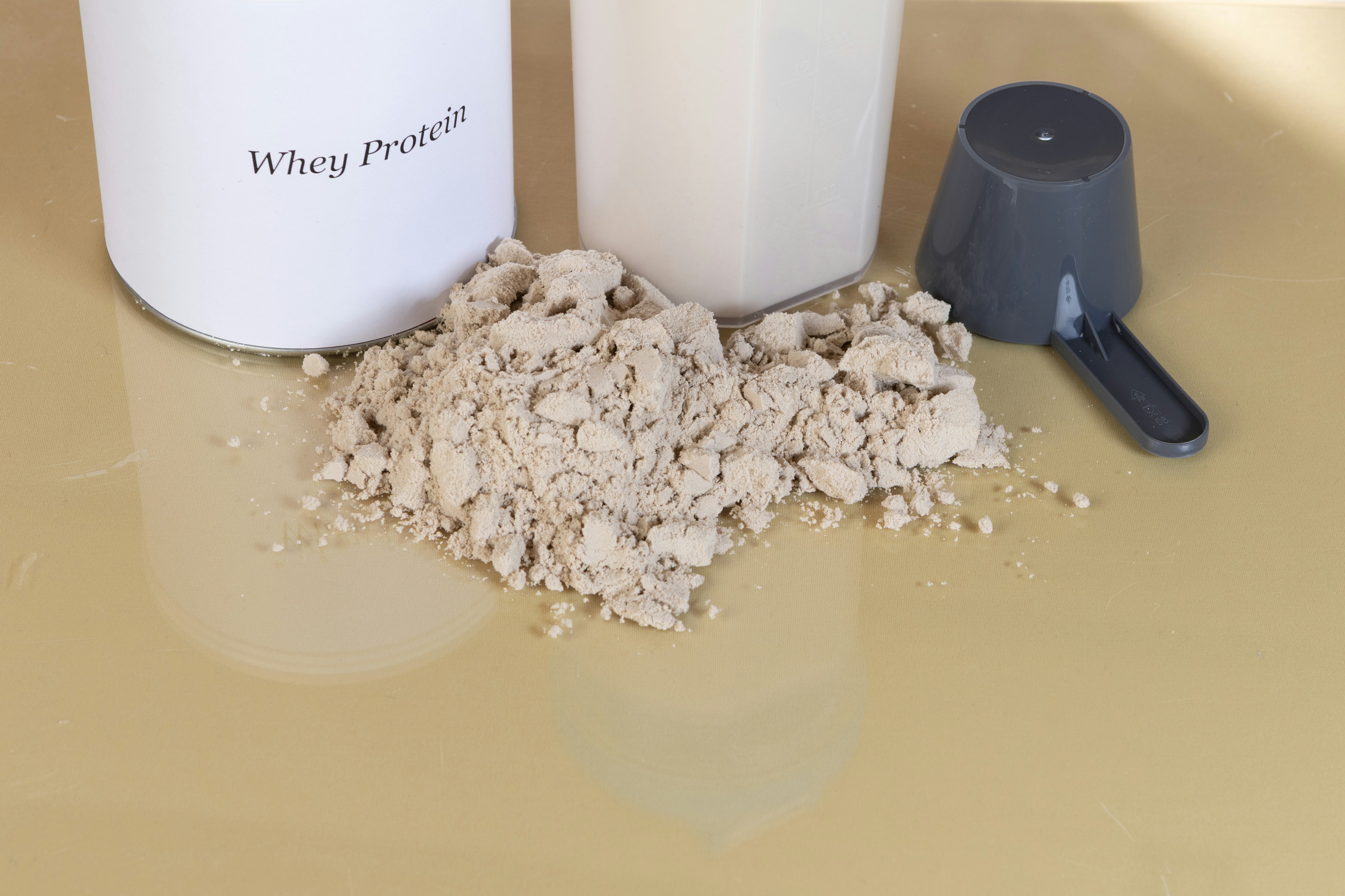 Pó de proteína de soro de leite com uma colher e recipiente