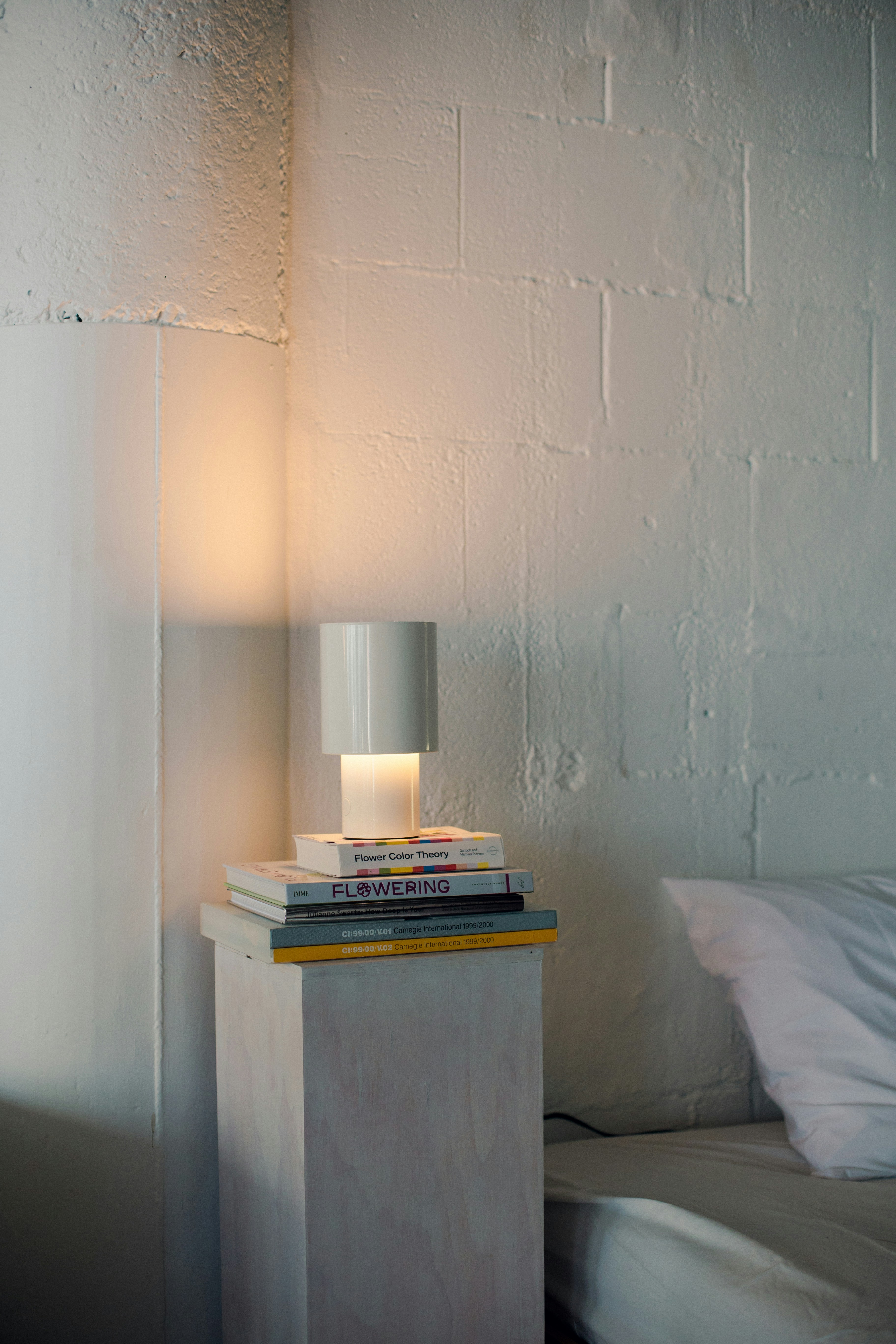 Sebuah lampu putih duduk di atas tumpukan buku.