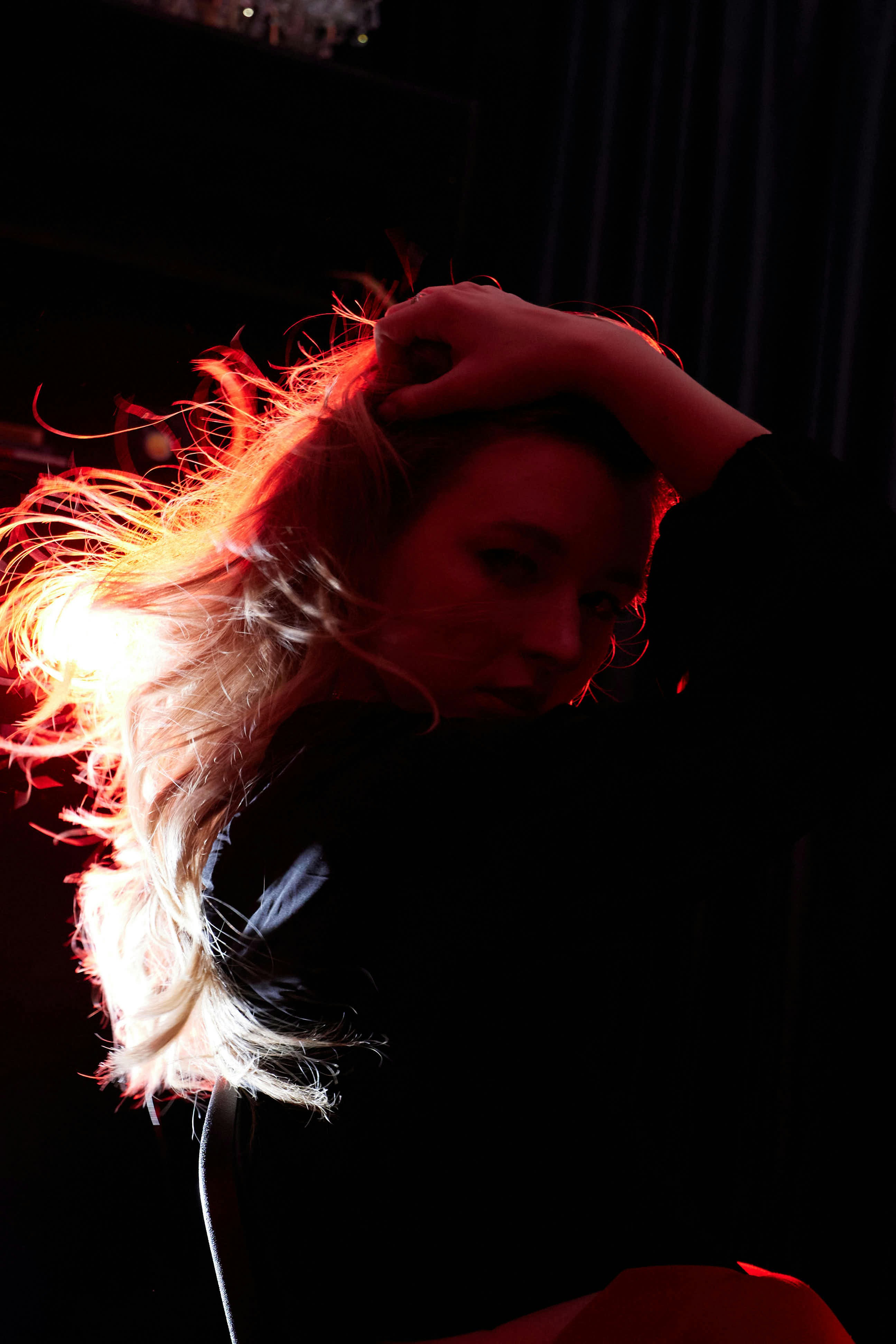 Woman with flowing hair illuminated by red light