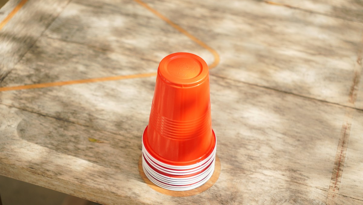 Orange plastic cup on a wooden table, often used in elementary PE games for coordination and balance activities.