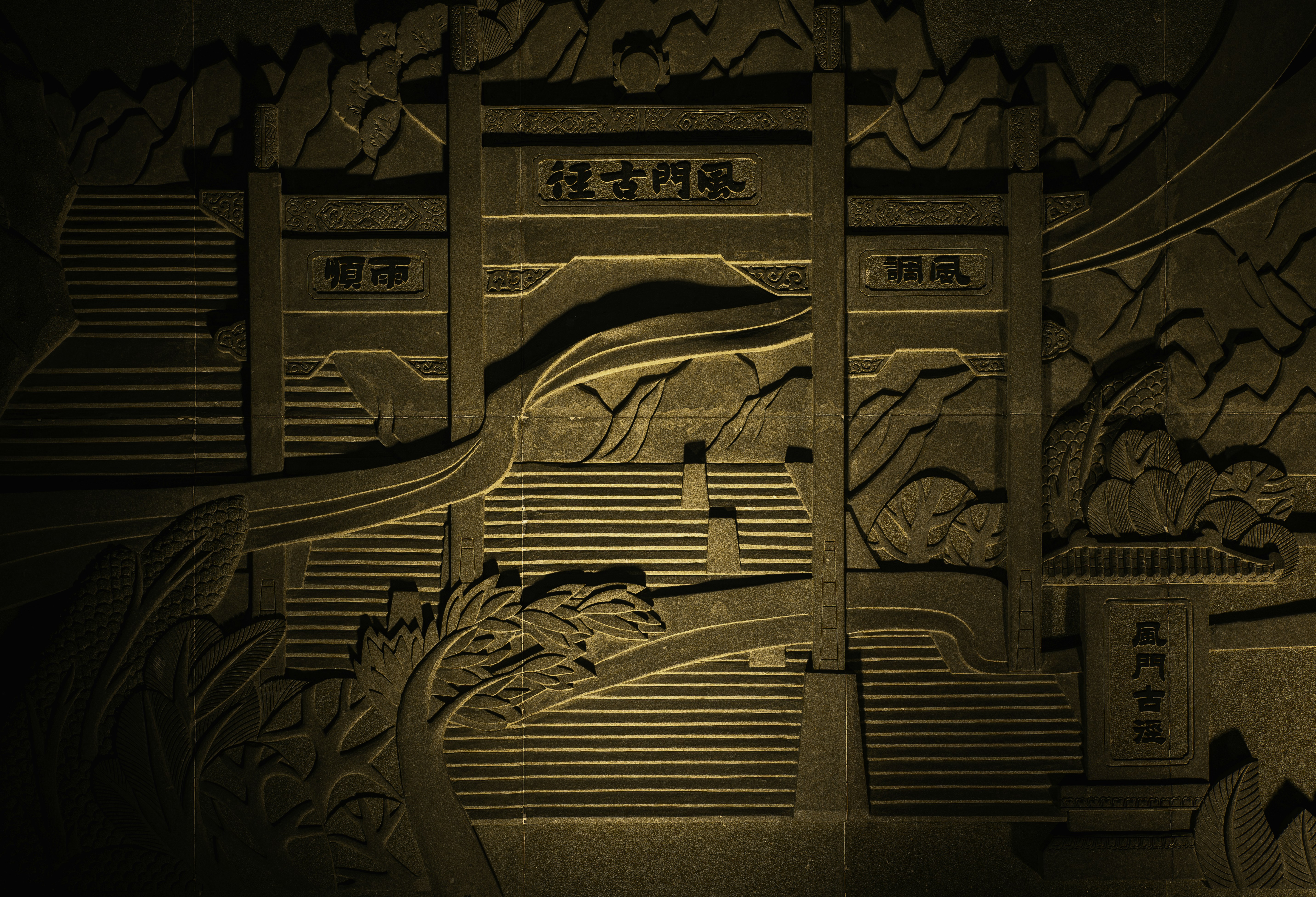 Intricate stone carving of a traditional gate with mountains.
