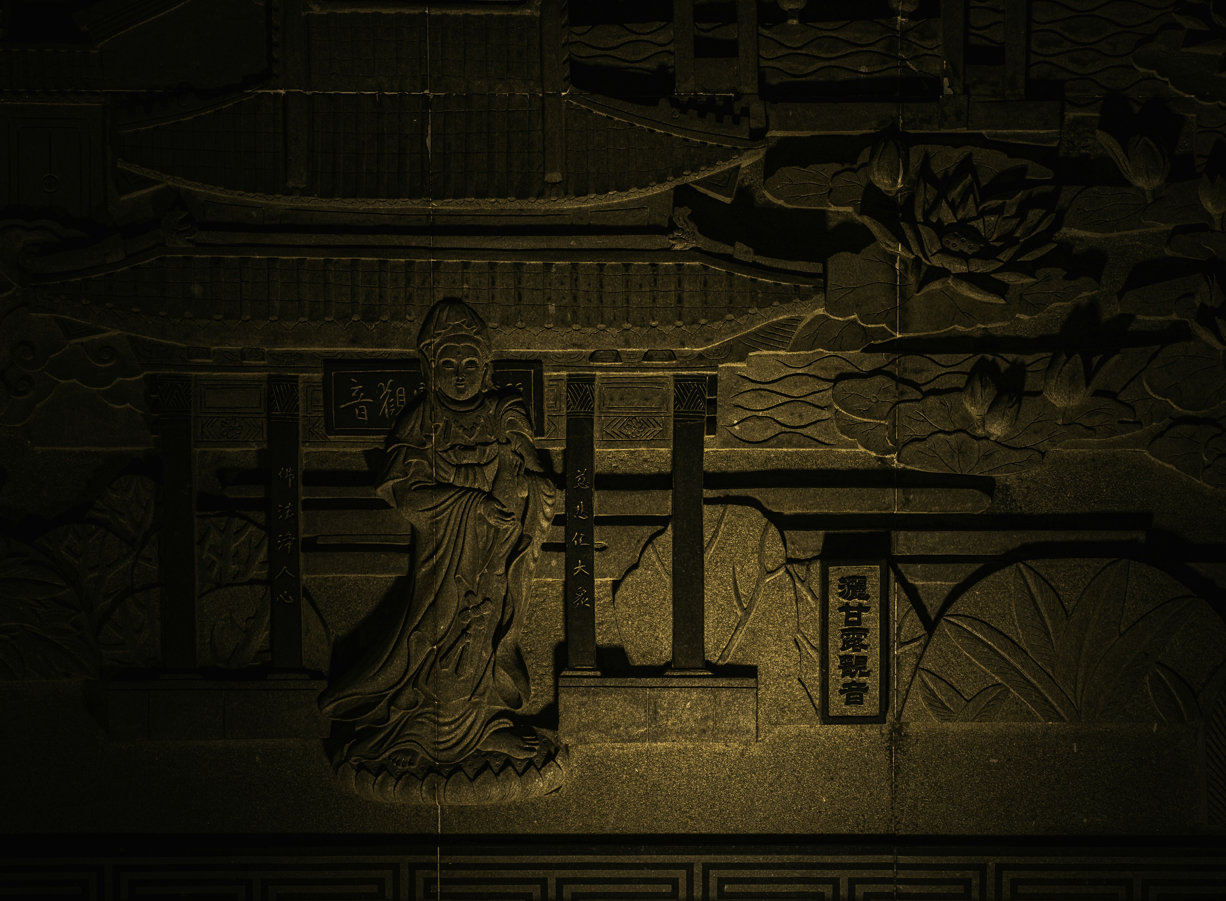 Ornate relief carving of an ancient asian building and figure.