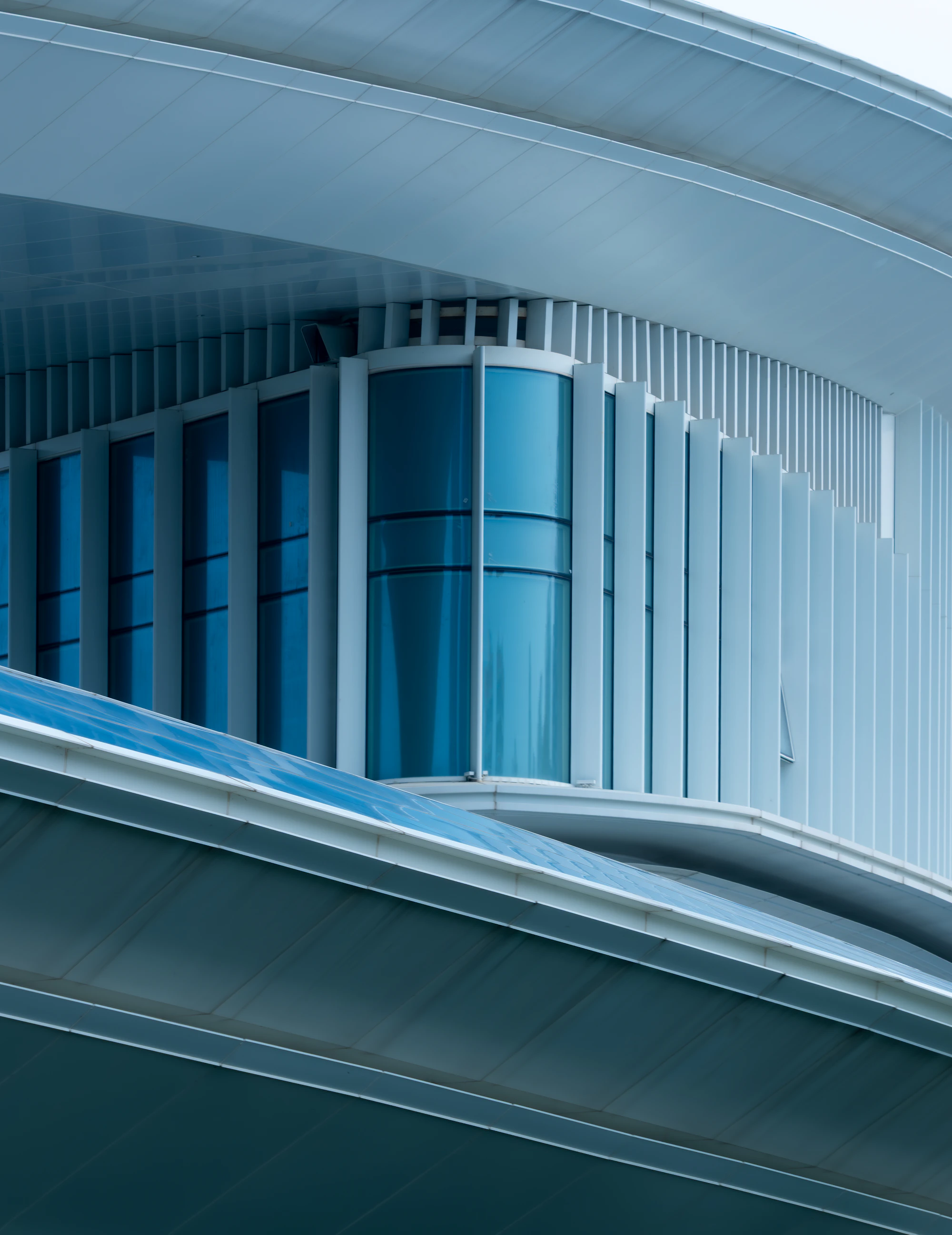 Curved glass architecture framed by repeating white structural fins