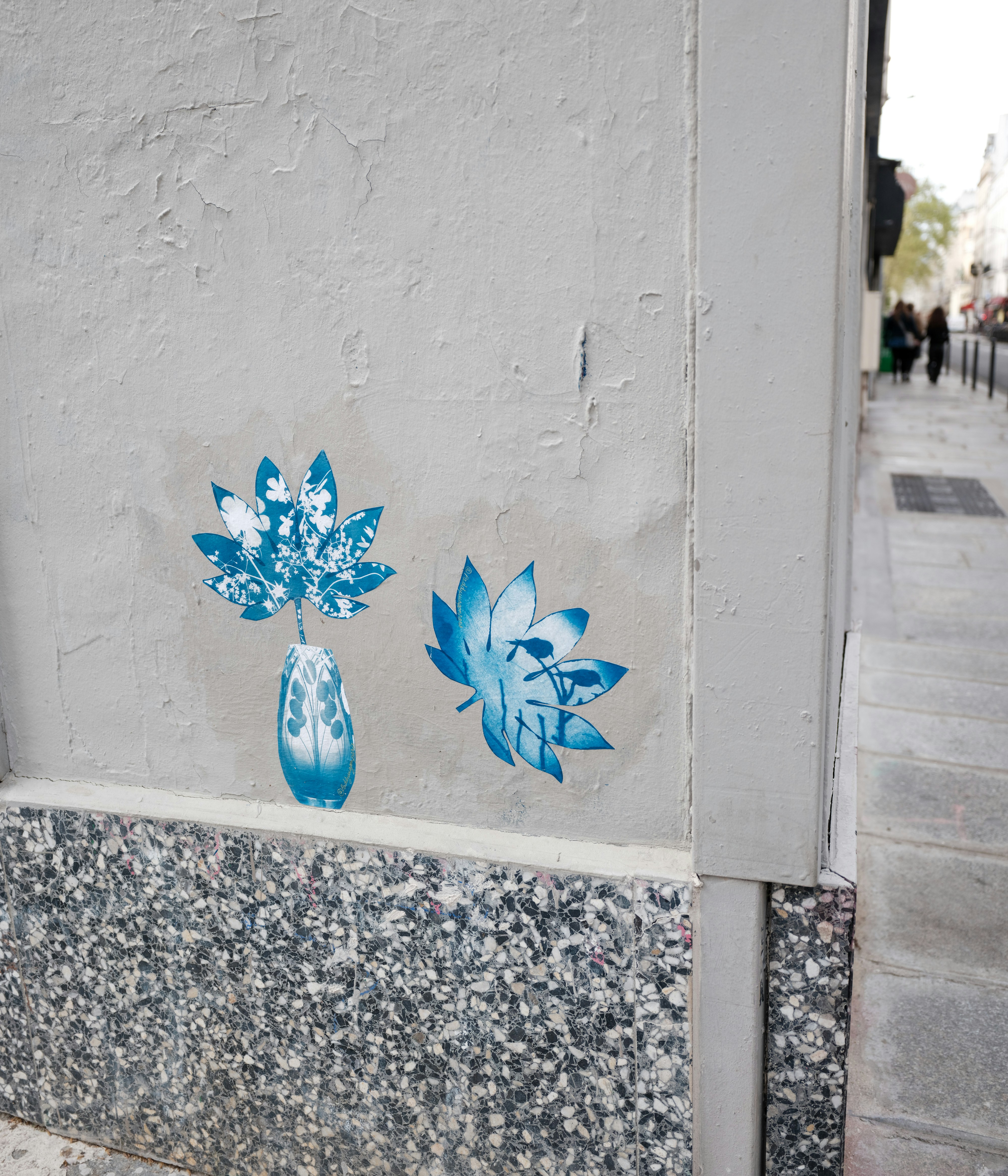 Arte floral azul em estêncil em uma parede texturizada.