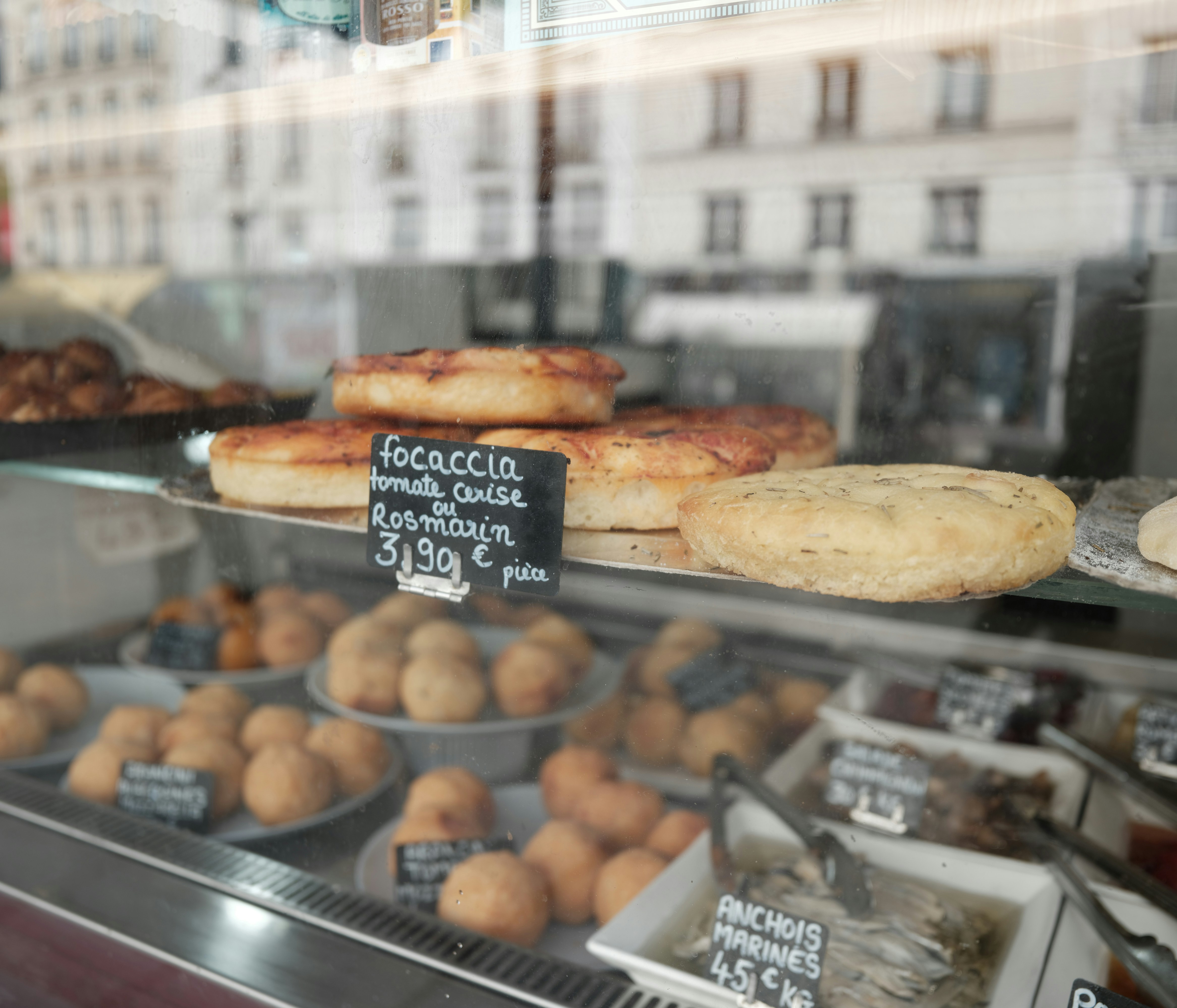Des focaccias et des pâtisseries exposées dans une vitrine de boulangerie.