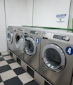 Row of silver washing machines in a laundromat.