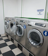 Row of silver washing machines in a laundromat.