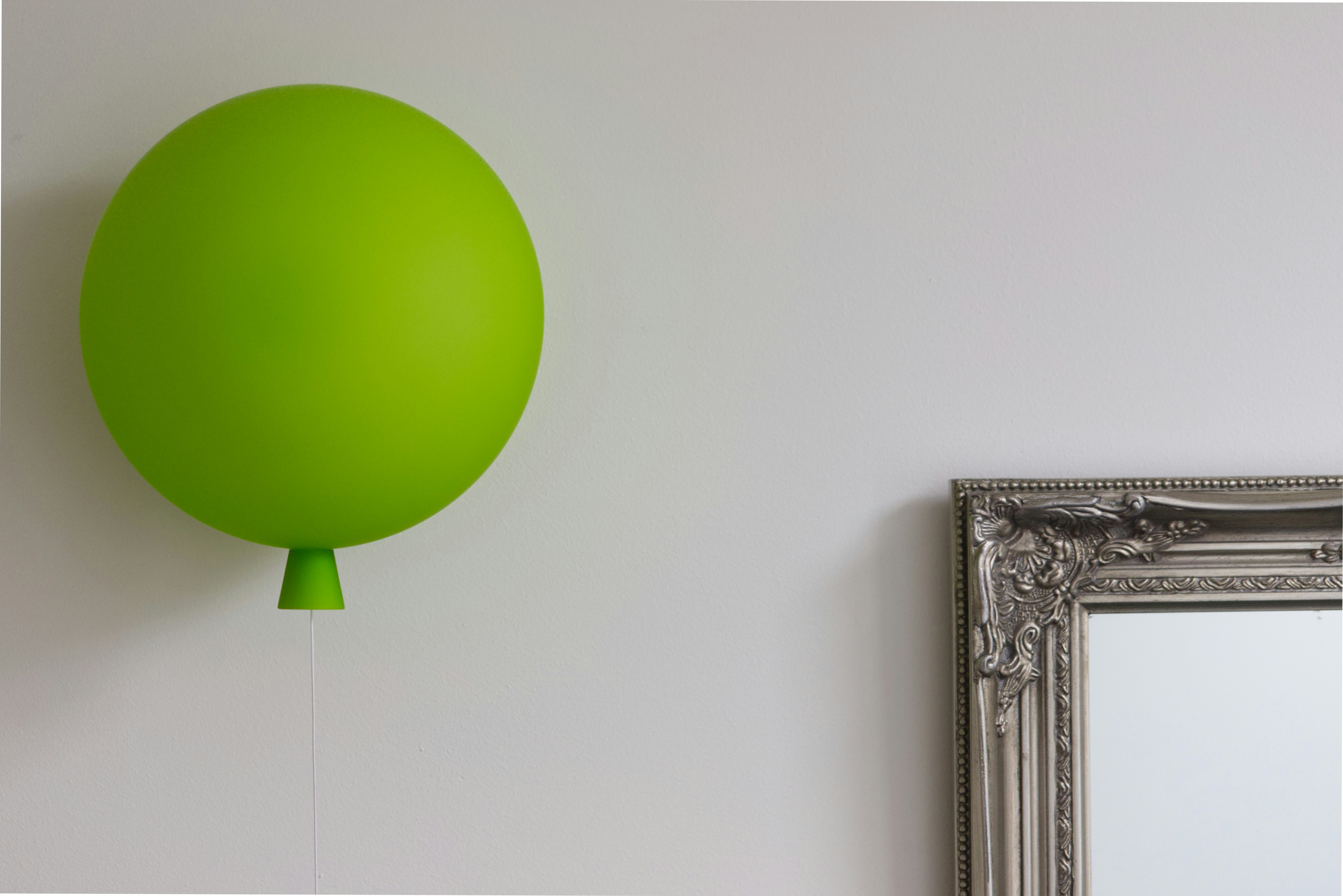 A bright green balloon decoration on a white wall.