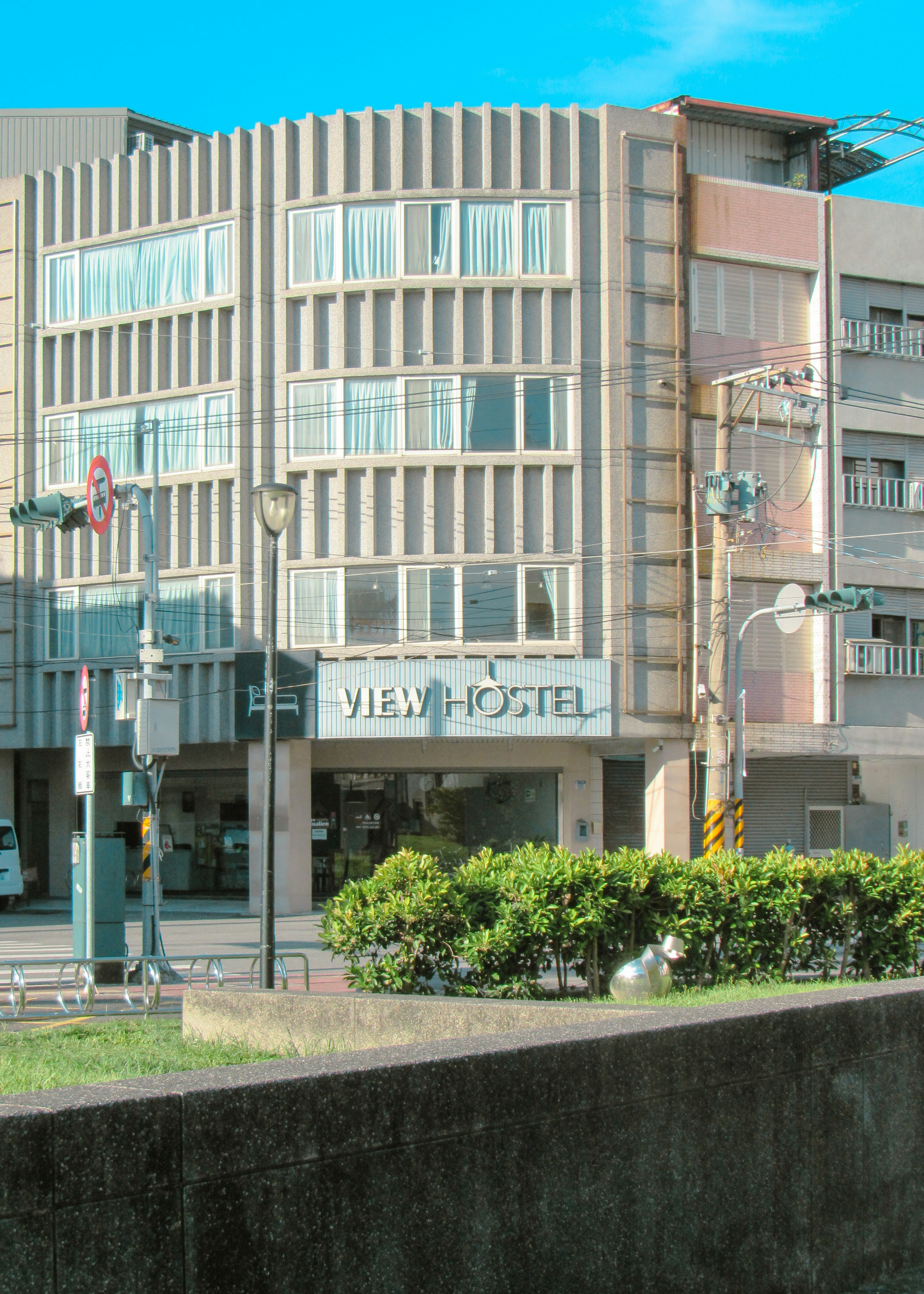 Modern hostel building with large windows and signage.