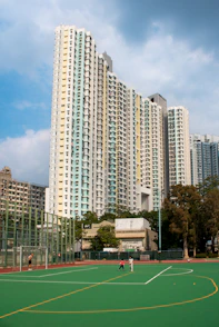 Tall apartment buildings overlook a green sports field.