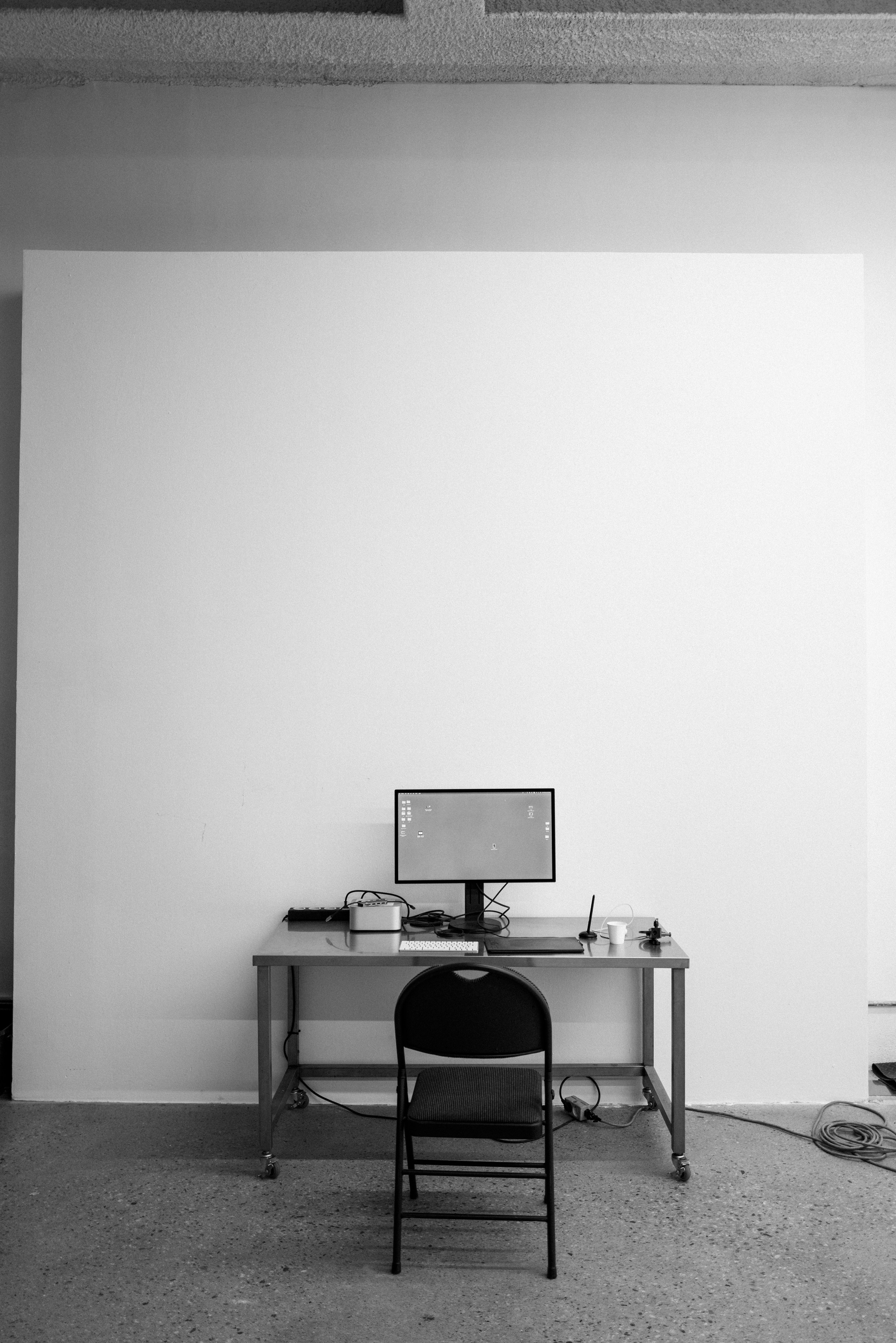 Schreibtisch mit Computer und Stuhl vor der weißen Wand