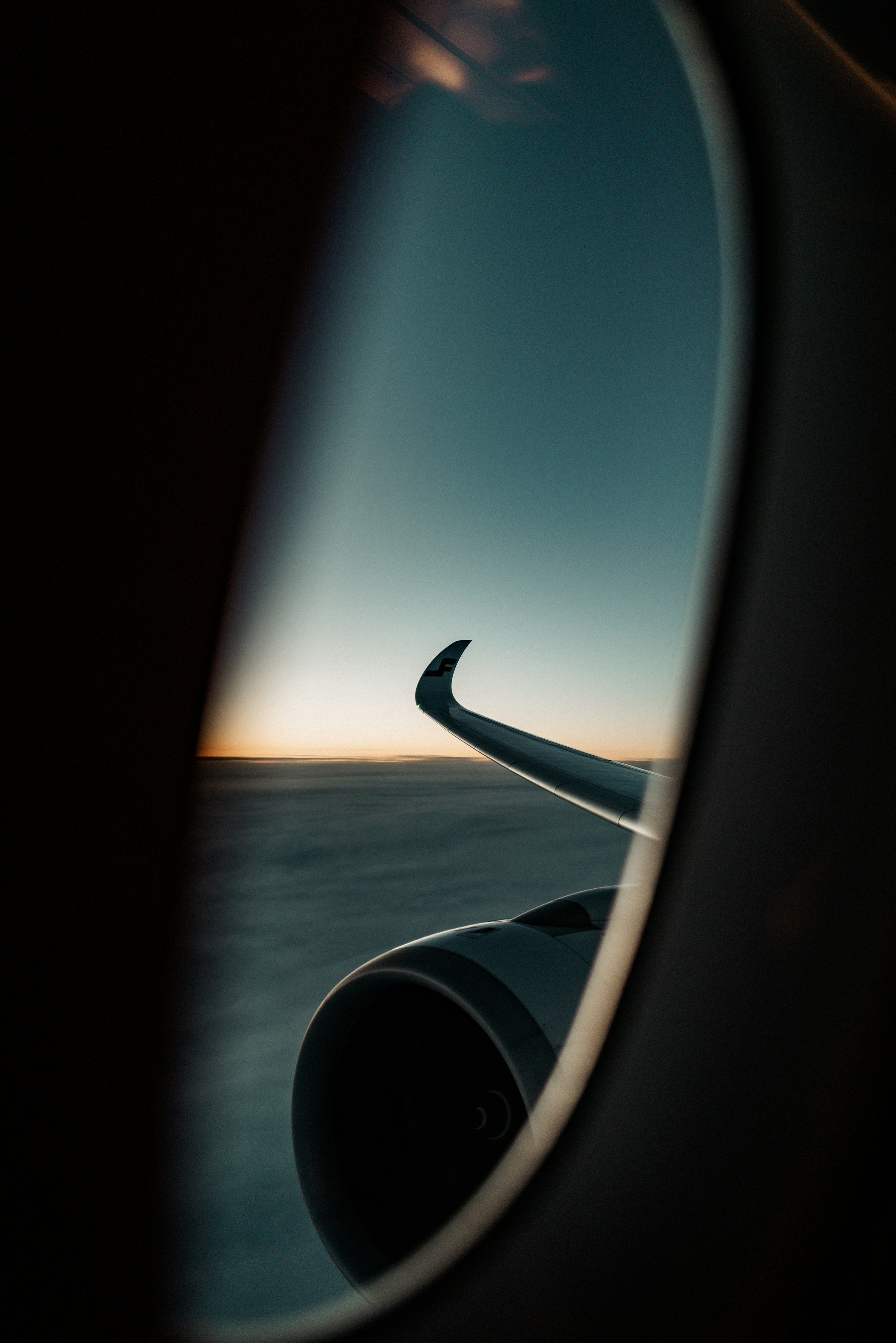 Airplane wing and engine seen through window at sunset.