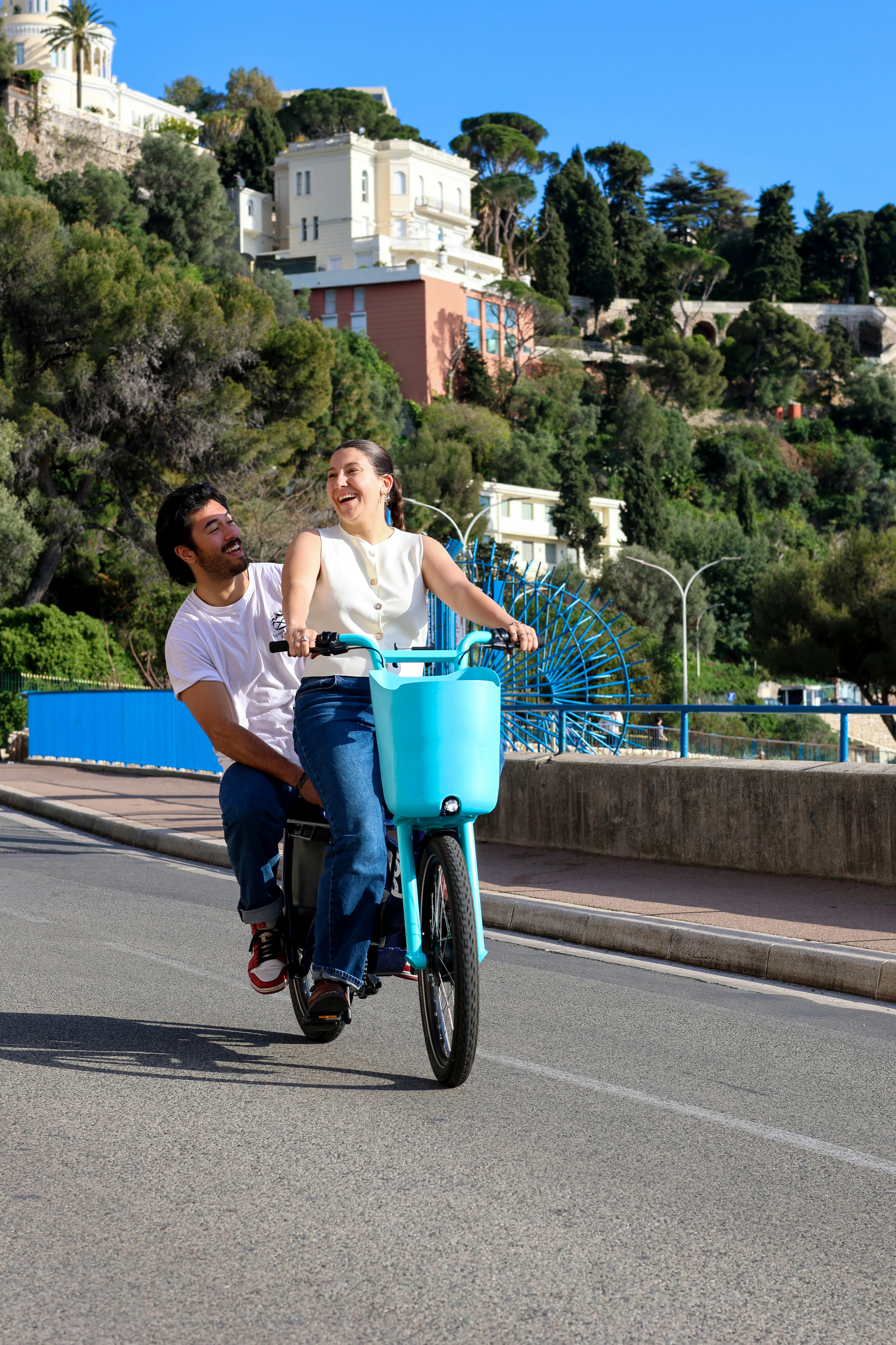 Paar fährt auf einem blauen Fahrrad am Meer entlang