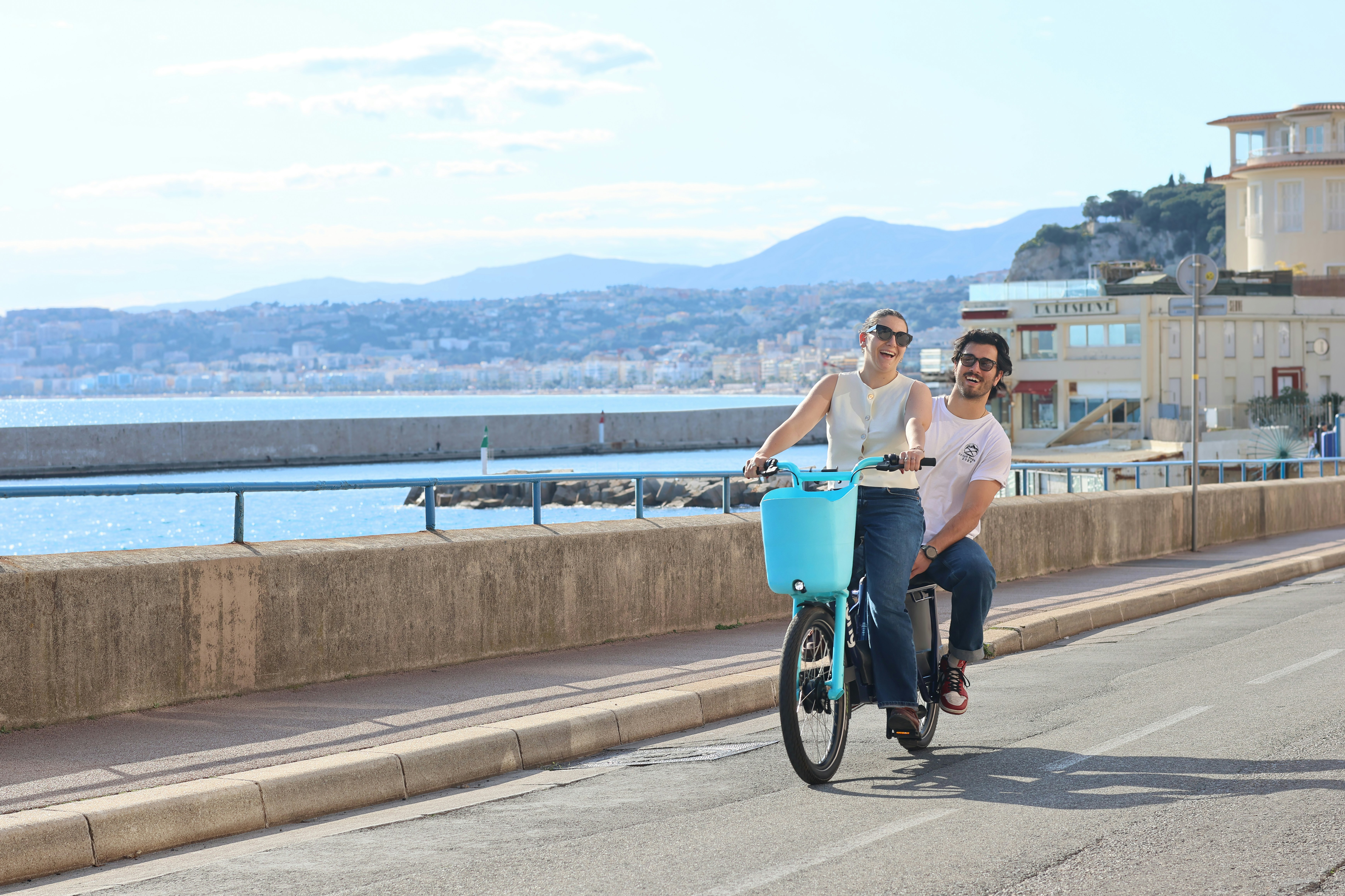 Ein Paar fährt mit einem Tandemfahrrad am Meer entlang.