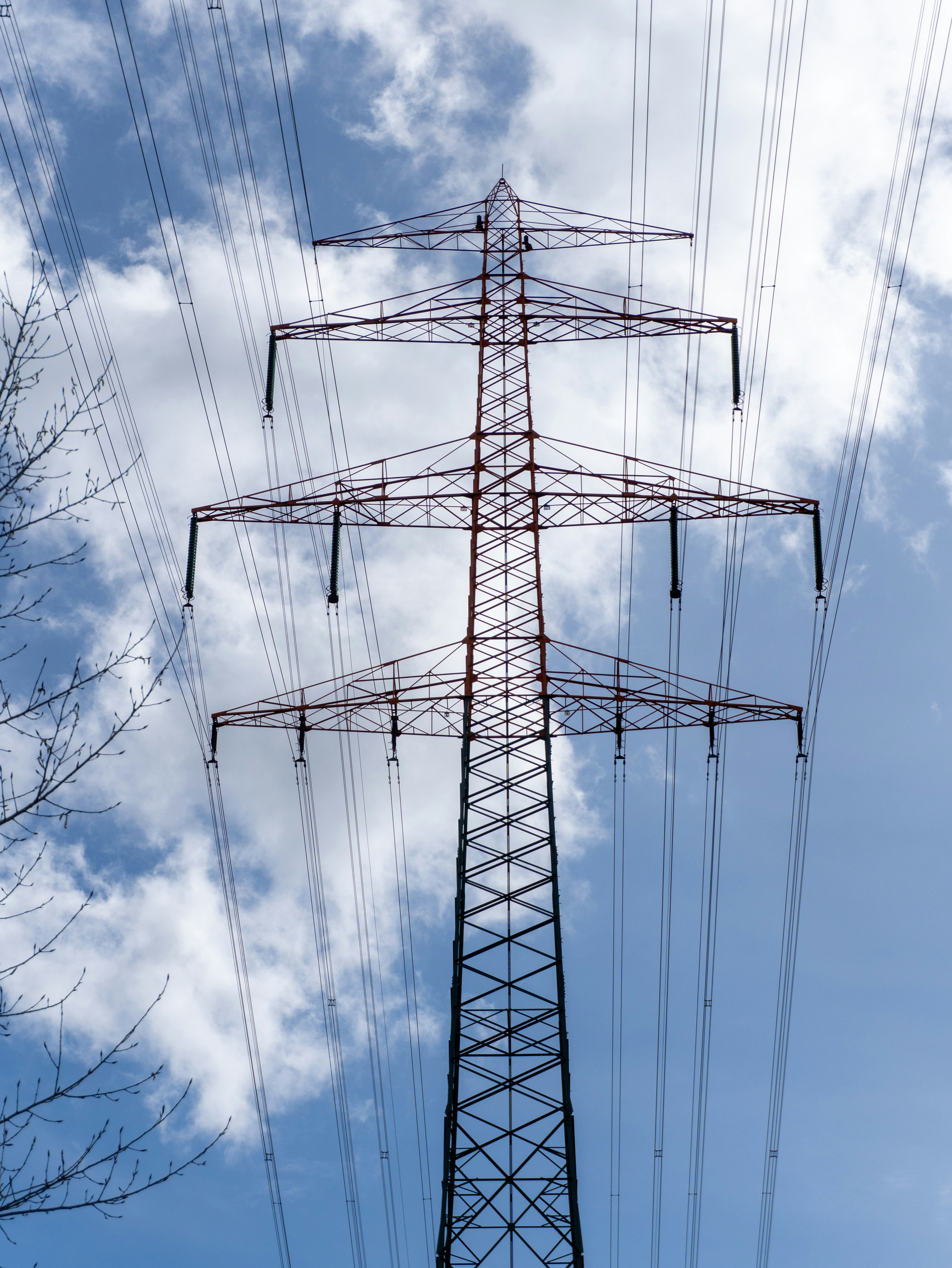 Un alto pilar eléctrico contra un cielo azul nublado.