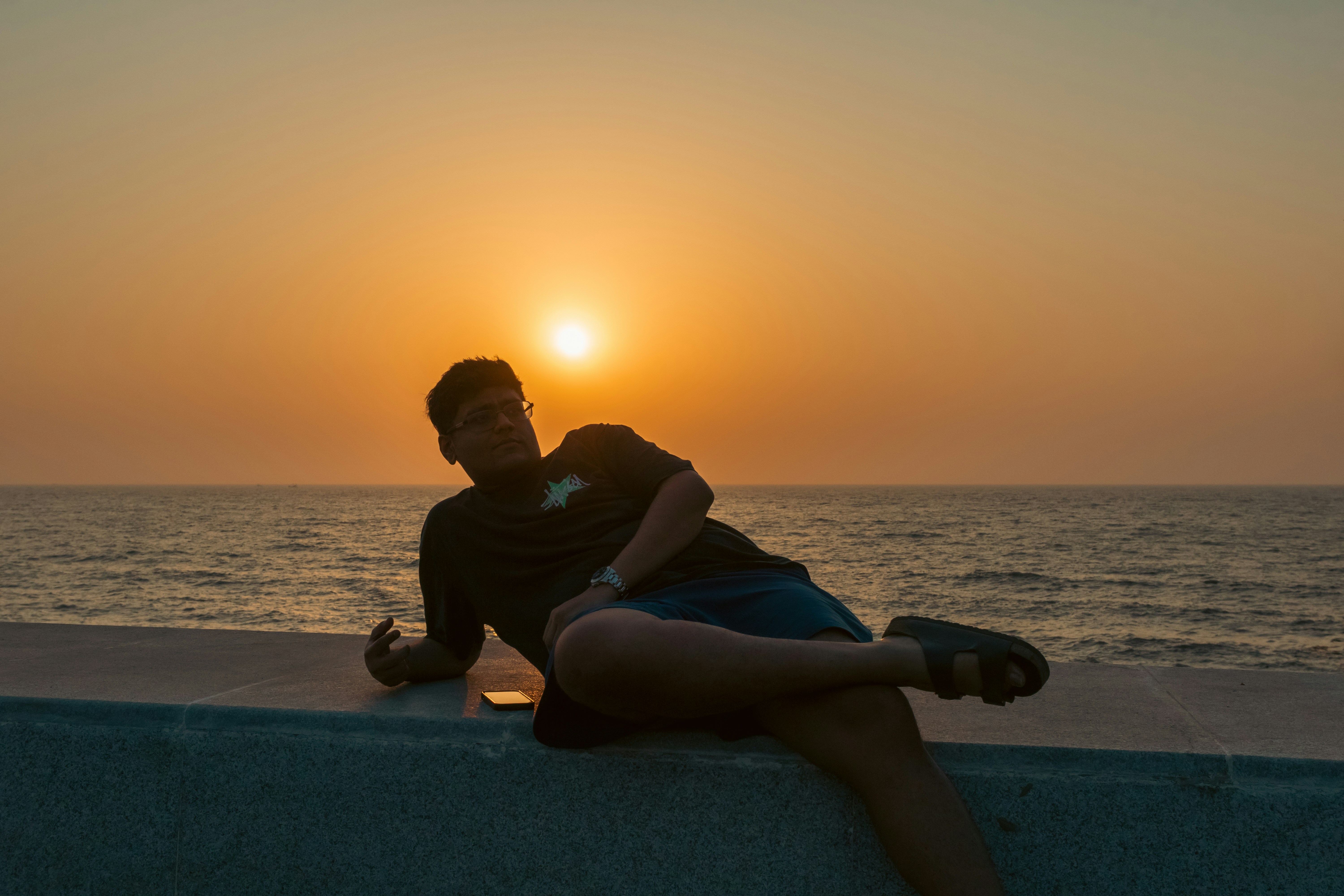 Man relaxing by the ocean at sunset.