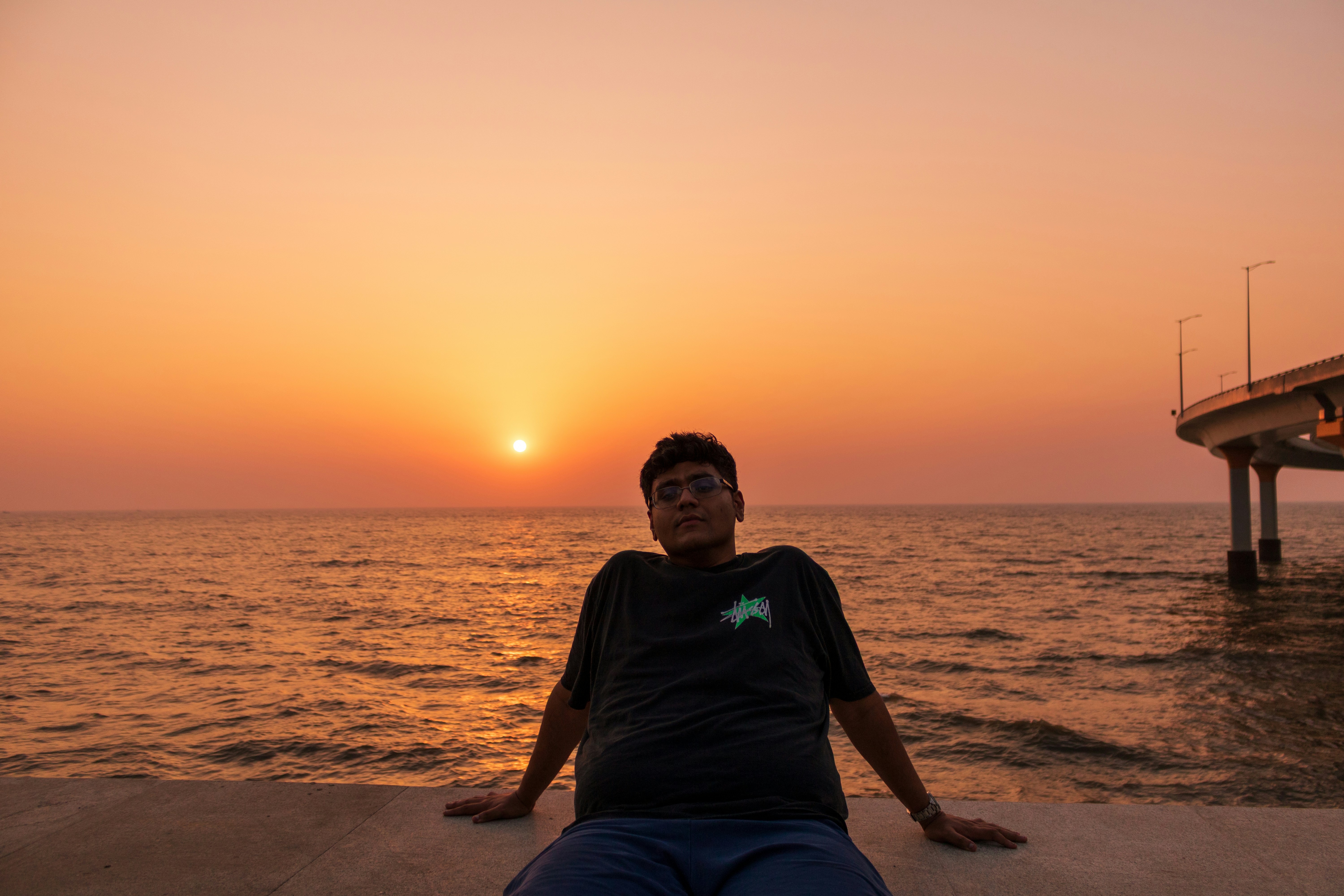 Man sitting by the ocean at sunset