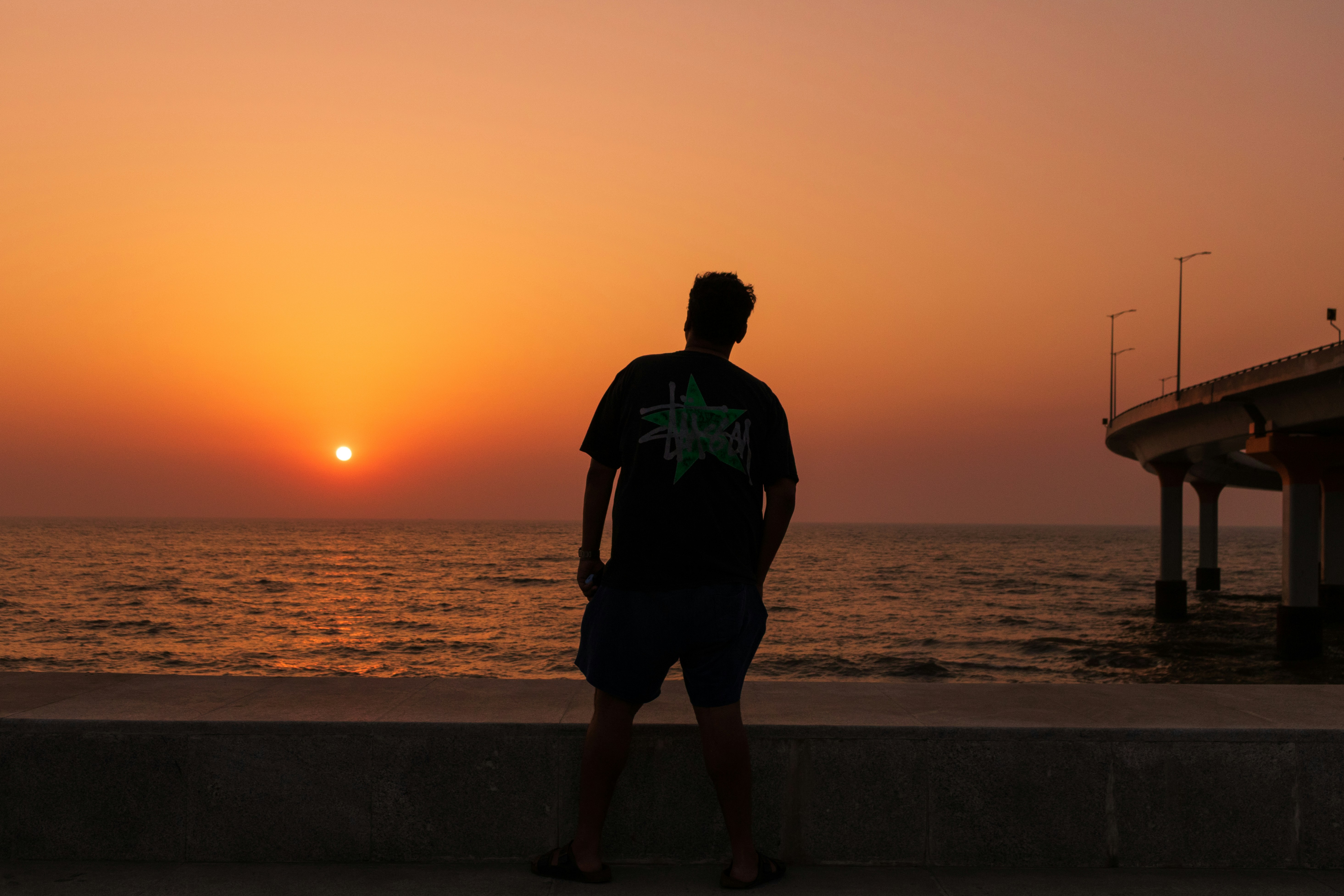 Man silhouetted against a vibrant ocean sunset