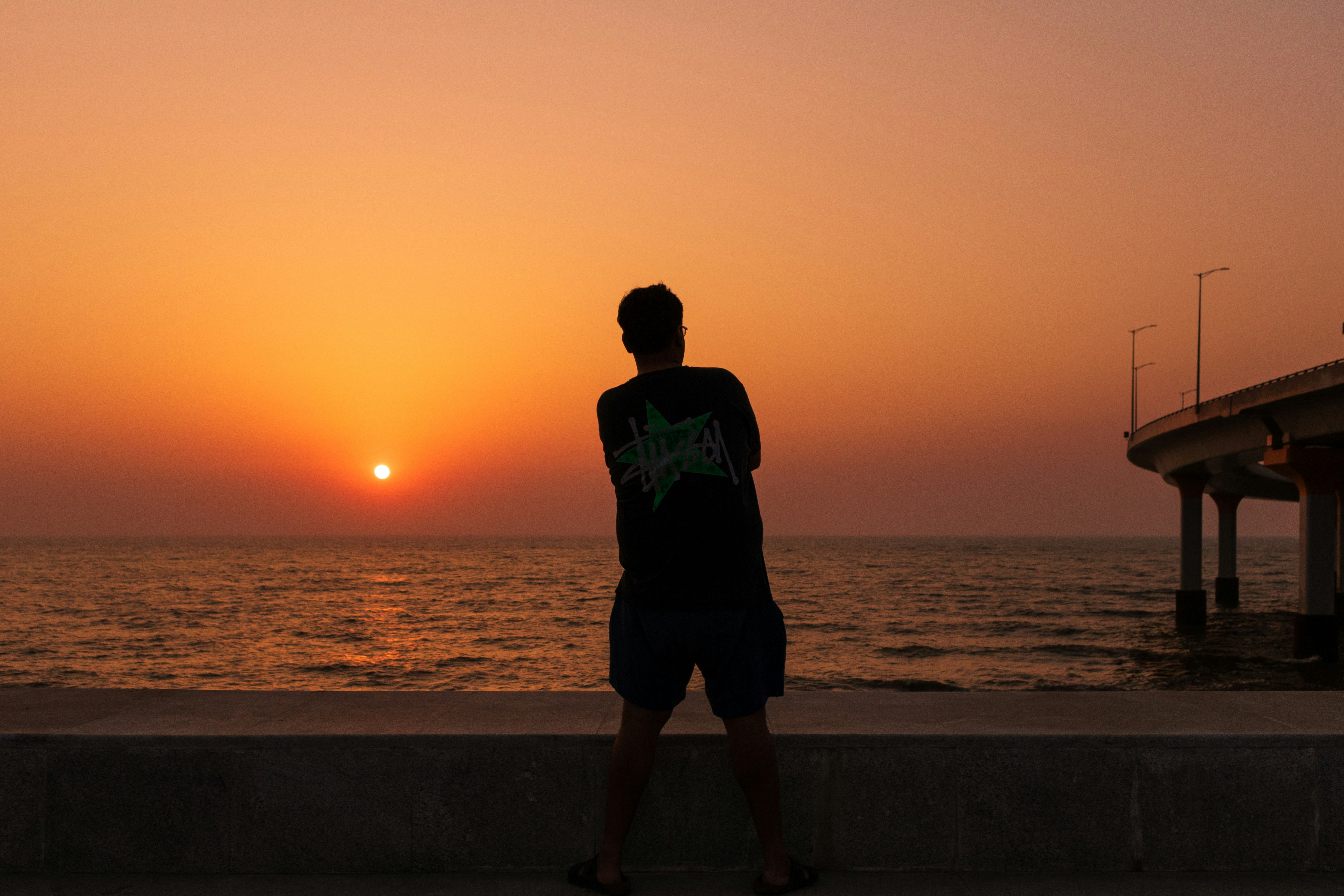Man silhouetted against a vibrant ocean sunset